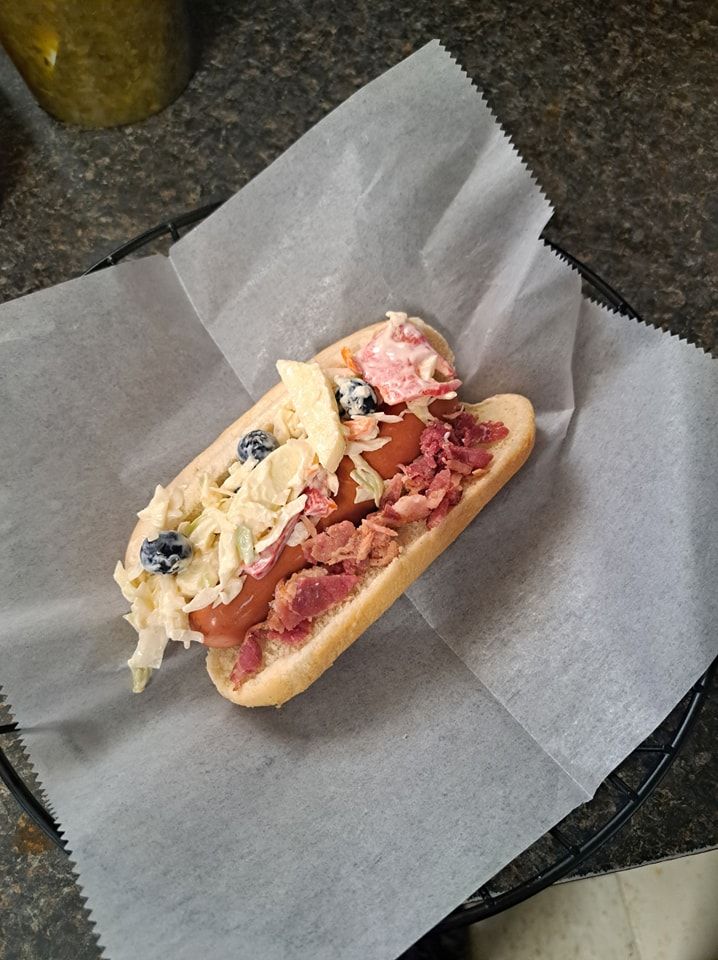 A hot dog with coleslaw and blueberries on a bun