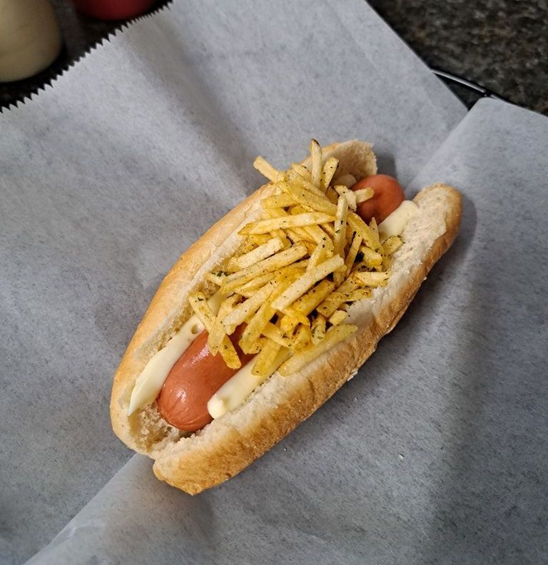 A hot dog with french fries on top of it
