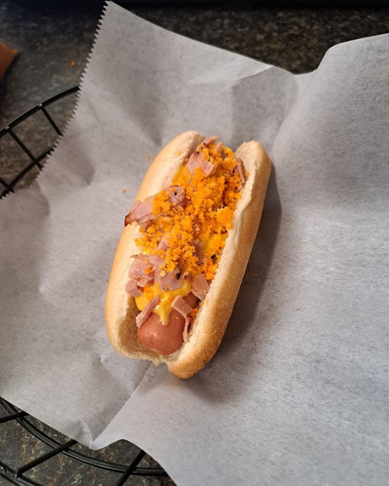 A hot dog with cheese and ham on a bun