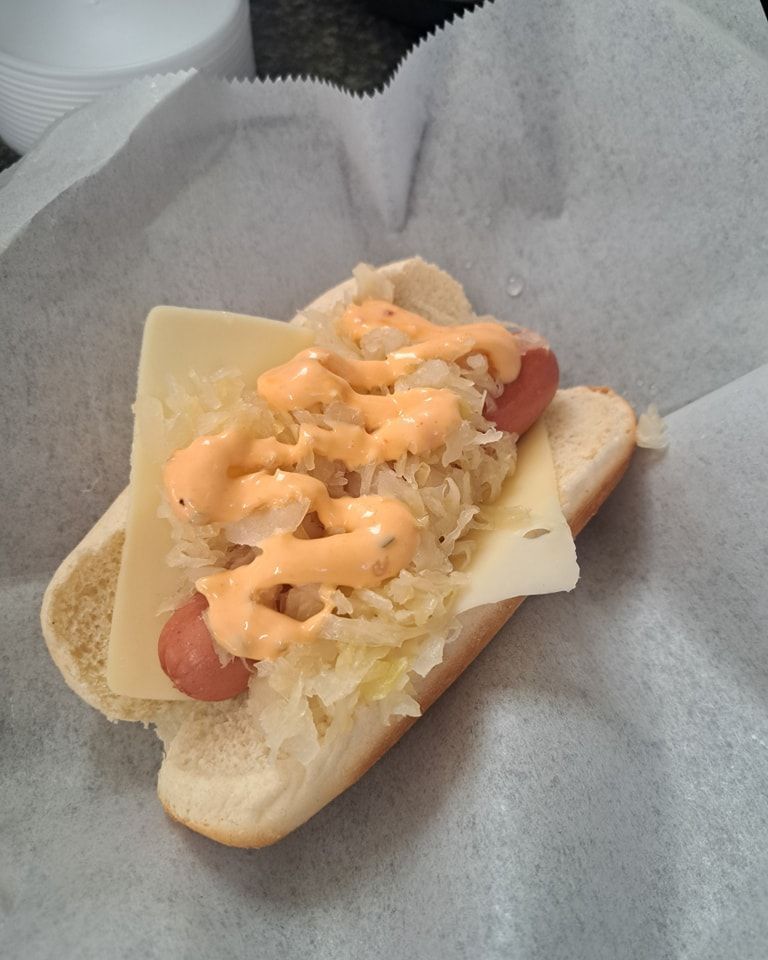 A hot dog with cheese and sauerkraut on a bun