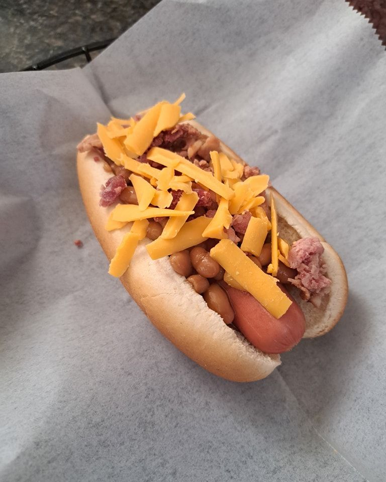 A hot dog with beans and cheese on a bun