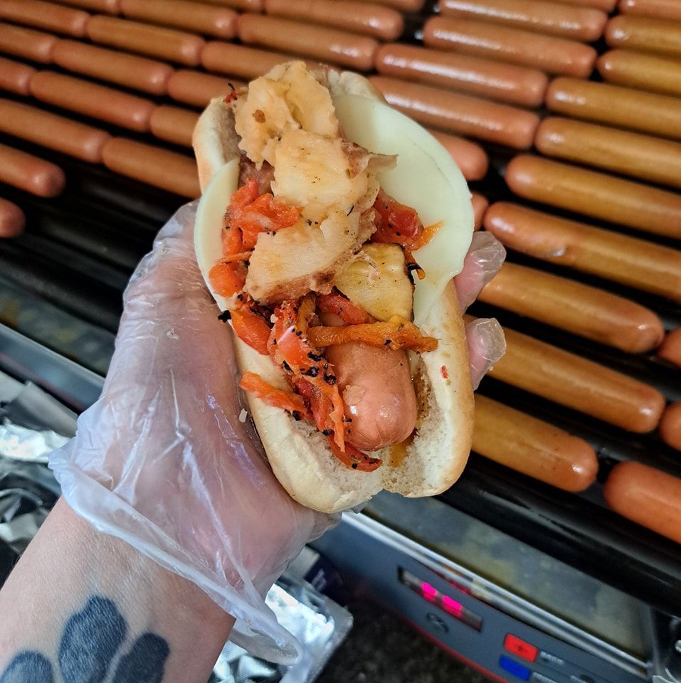 A person is holding a hot dog in front of a bunch of hot dogs