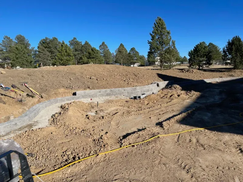 A construction site with a lot of dirt and trees in the background
