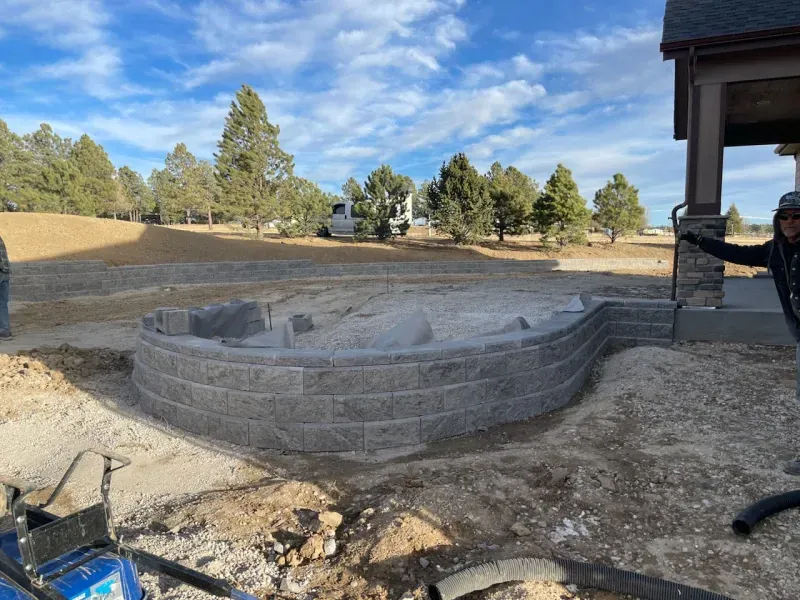 A man is standing in front of a brick wall that is being built.