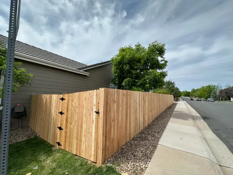 A wooden fence along a sidewalk next to a house