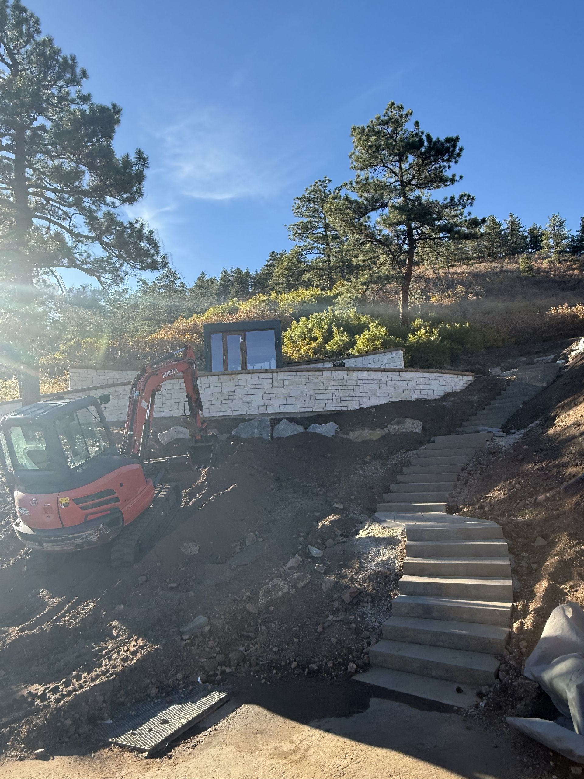 An excavator is sitting on top of a hill next to stairs.