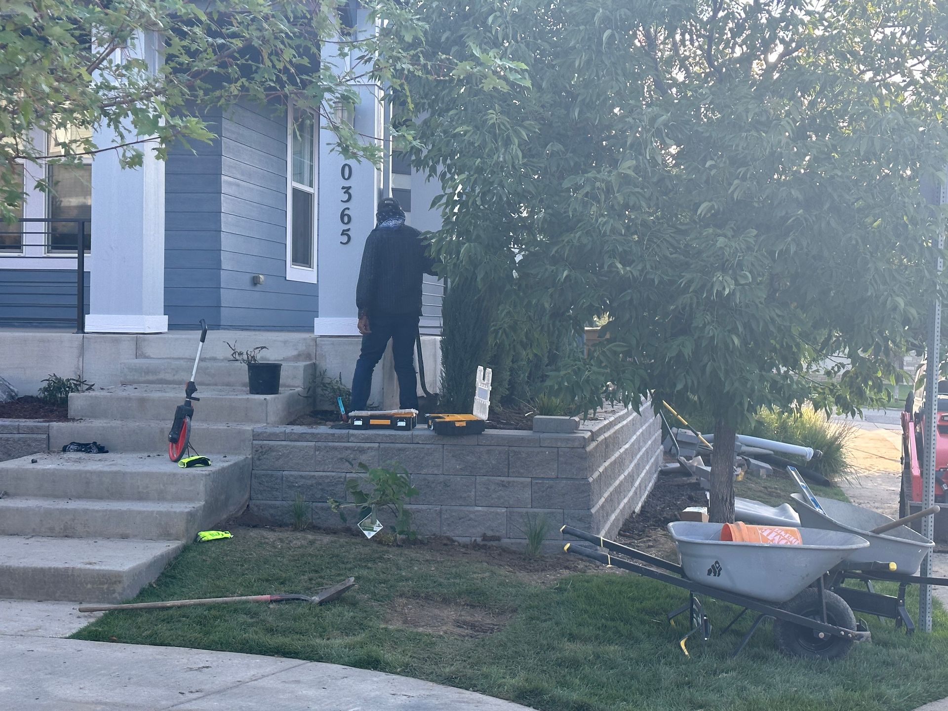 A man is working on a brick wall in front of a house.