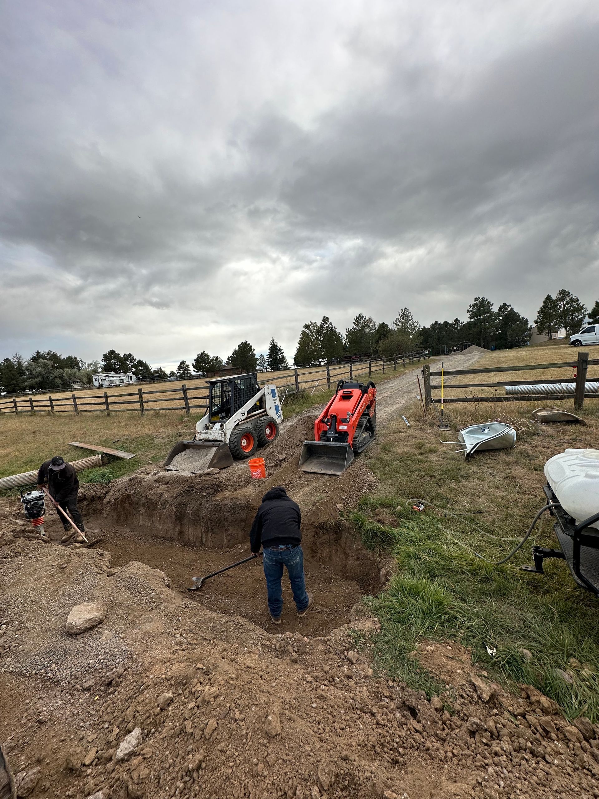 A group of people are digging a hole in the dirt in a field.