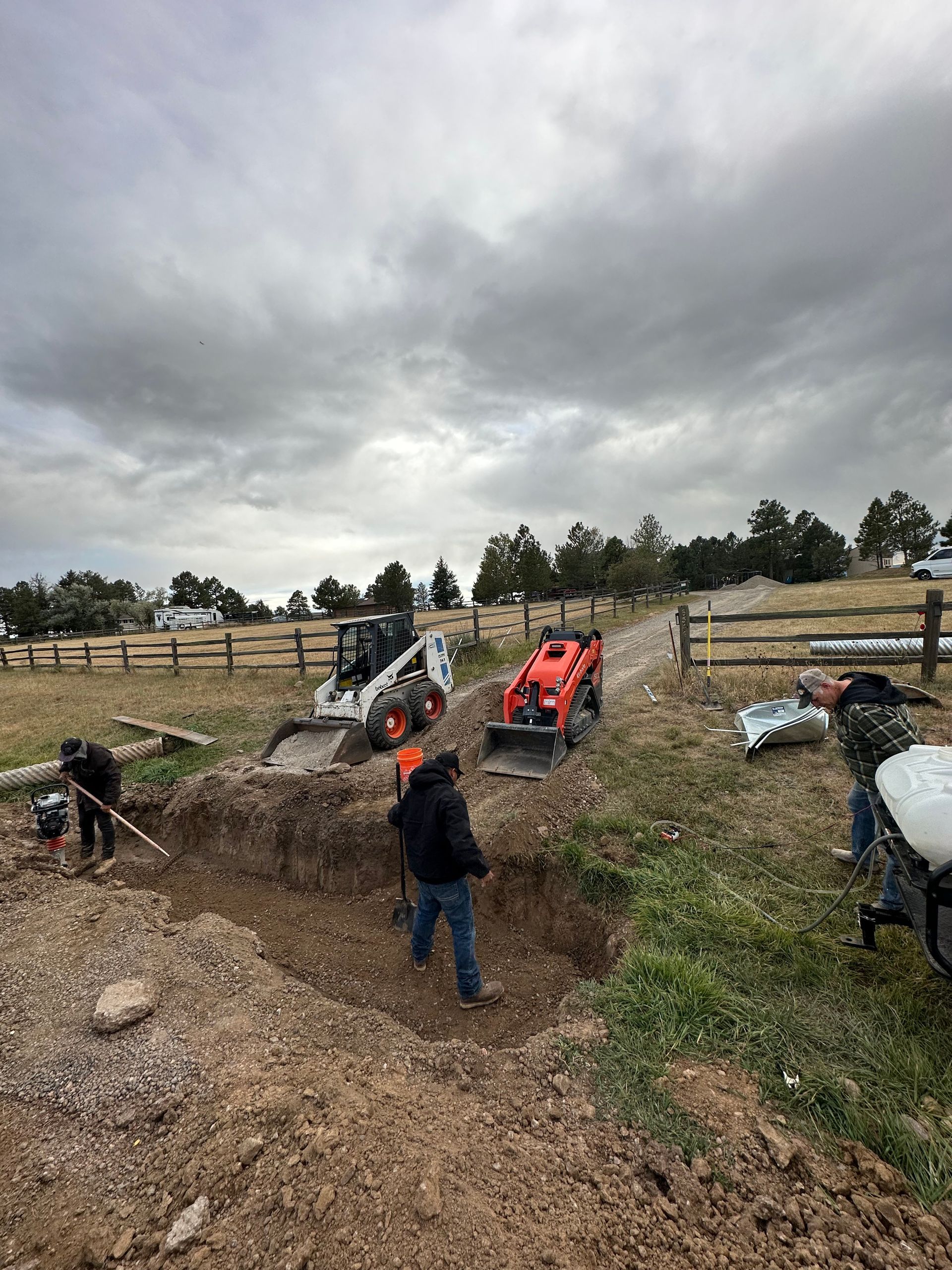 A group of people are digging a hole in the dirt in a field.