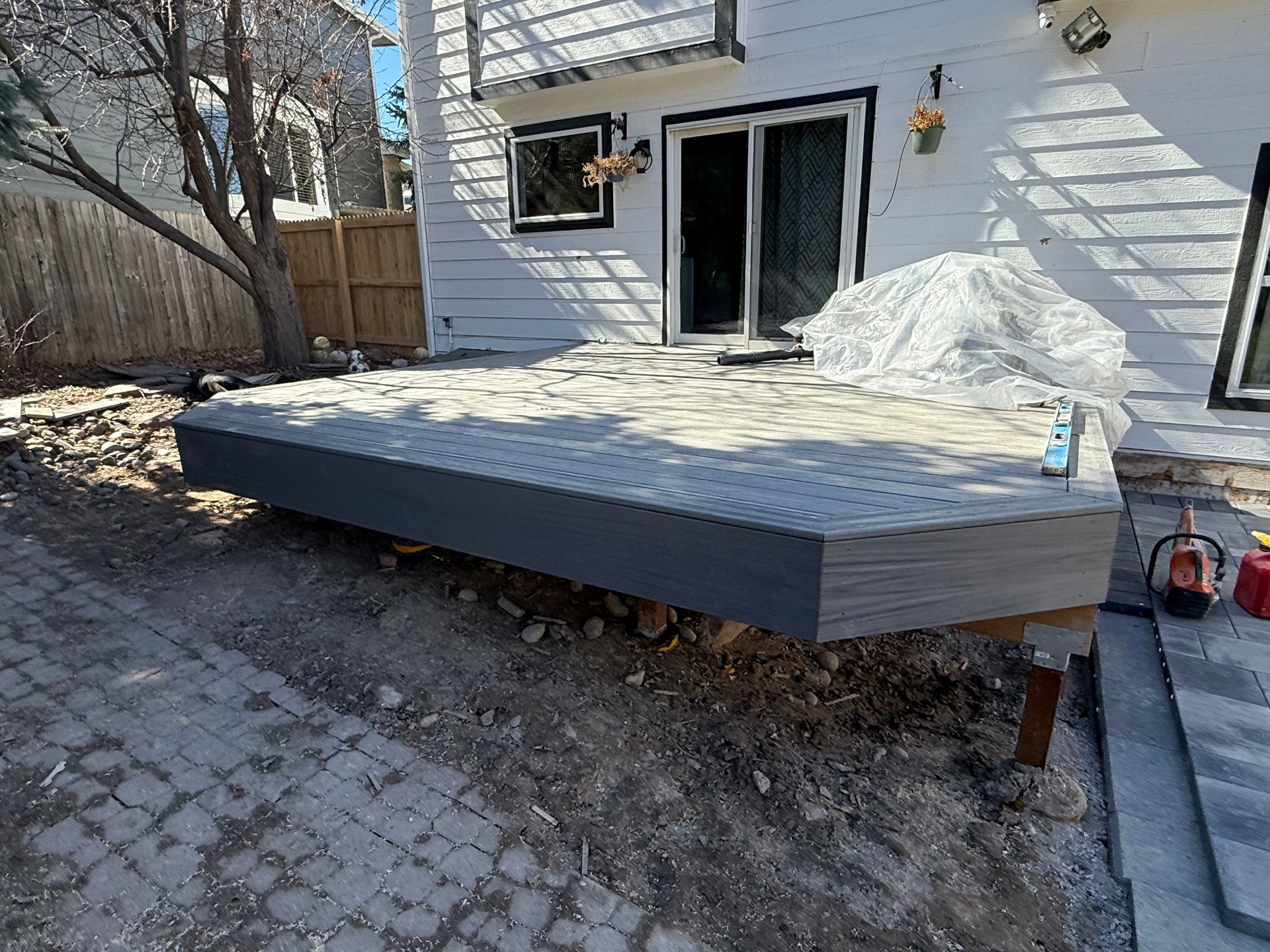 A wooden deck is being built in front of a white house.
