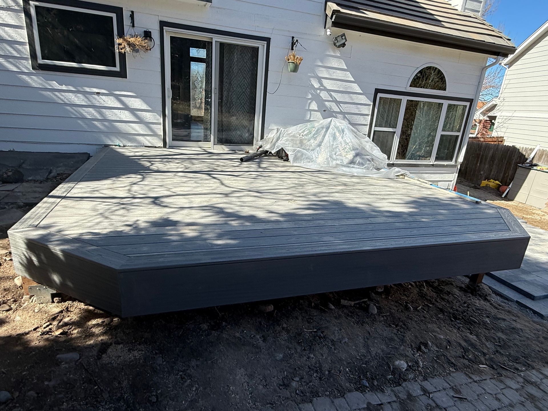 A large wooden deck is sitting in front of a white house.