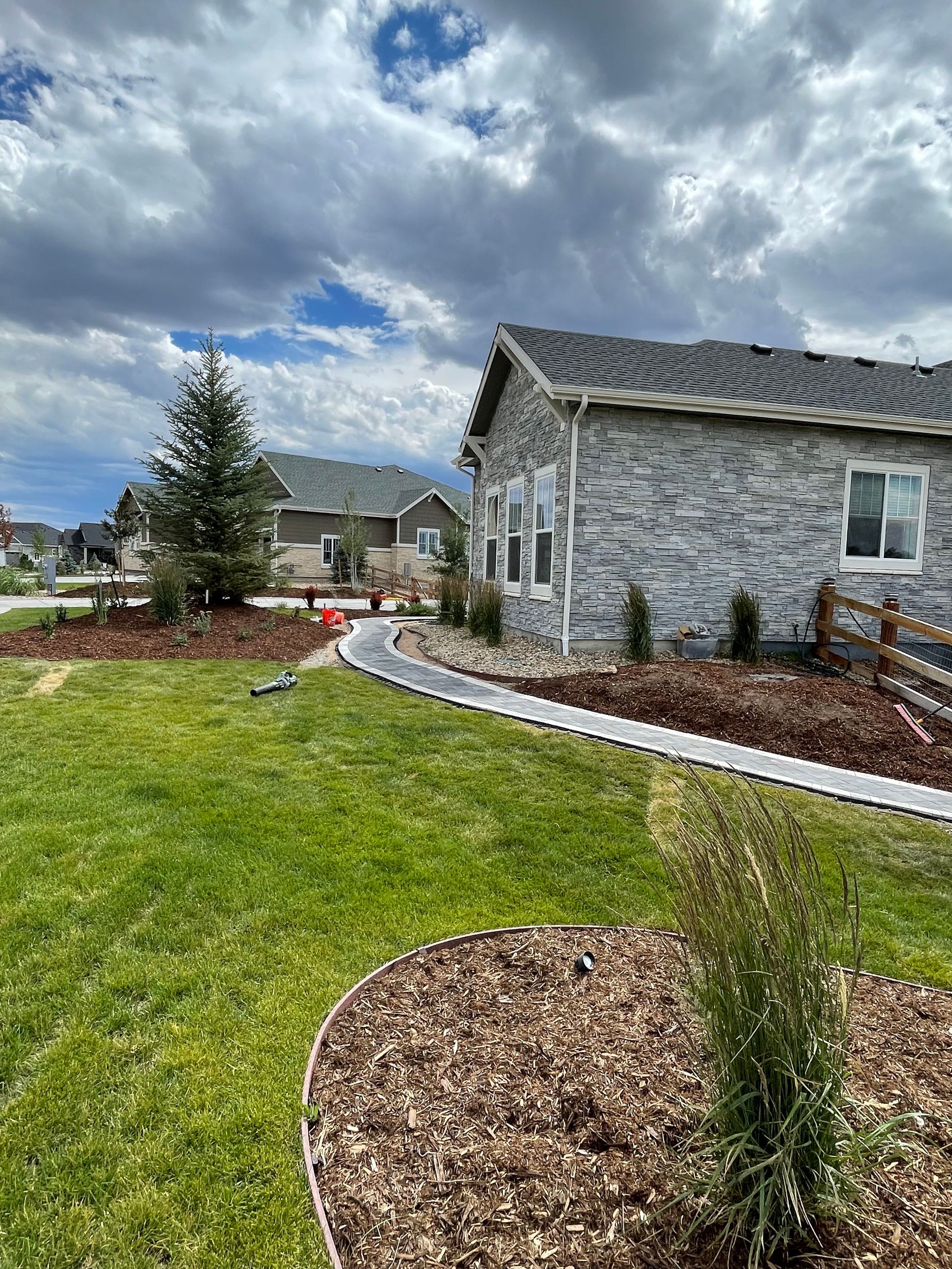 A brick house with a fence and a lush green lawn in front of it.