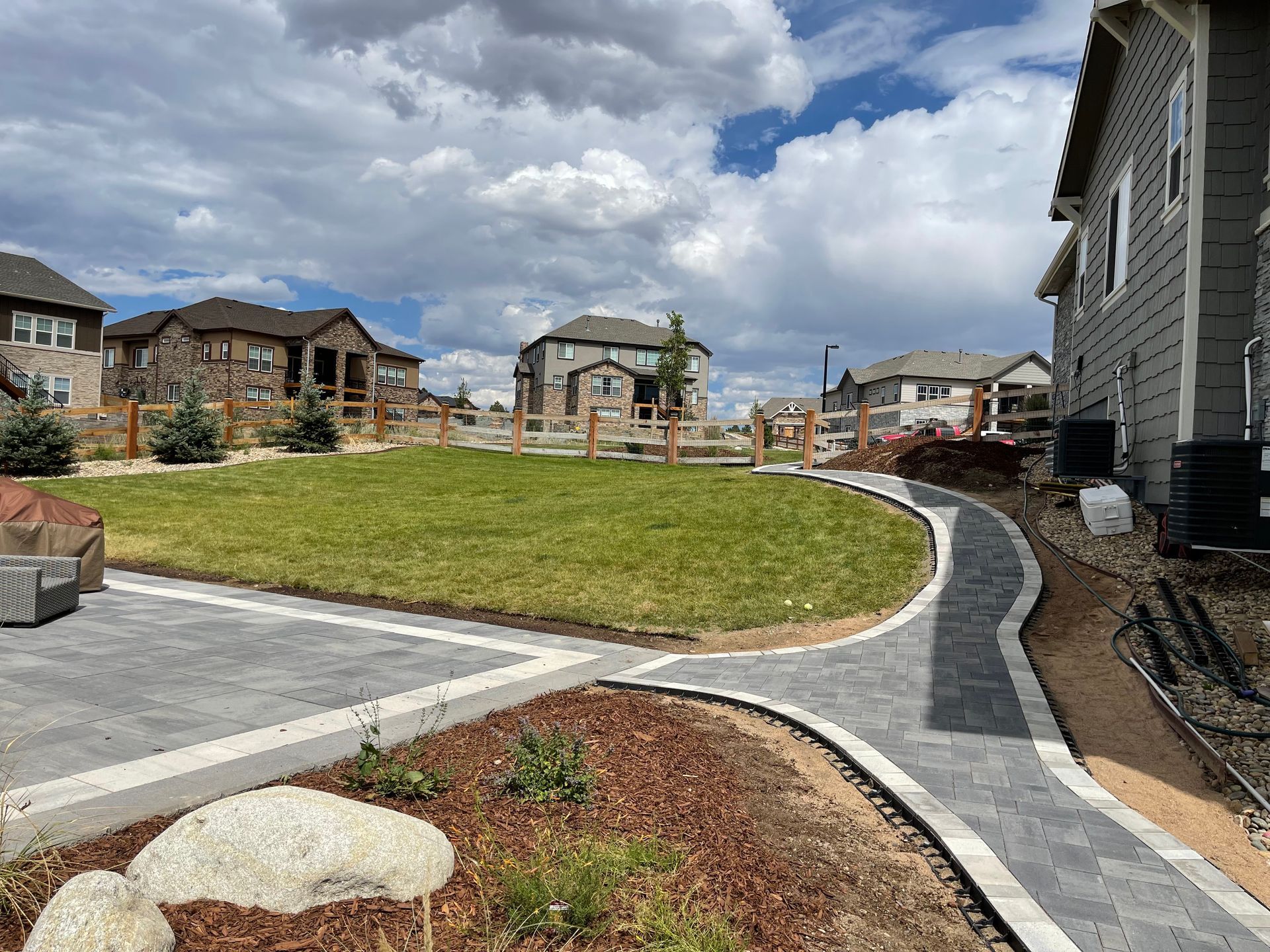 A brick walkway leading to a house in a residential area.