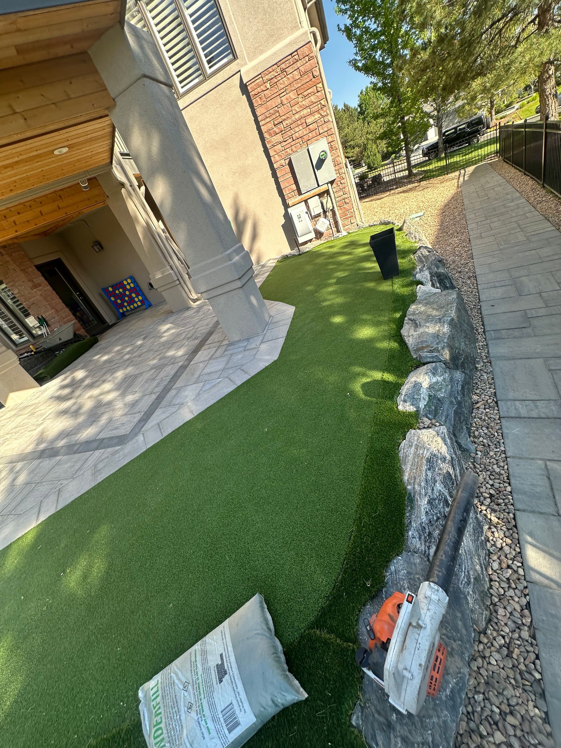 A bag of grass is laying on the ground in front of a house.
