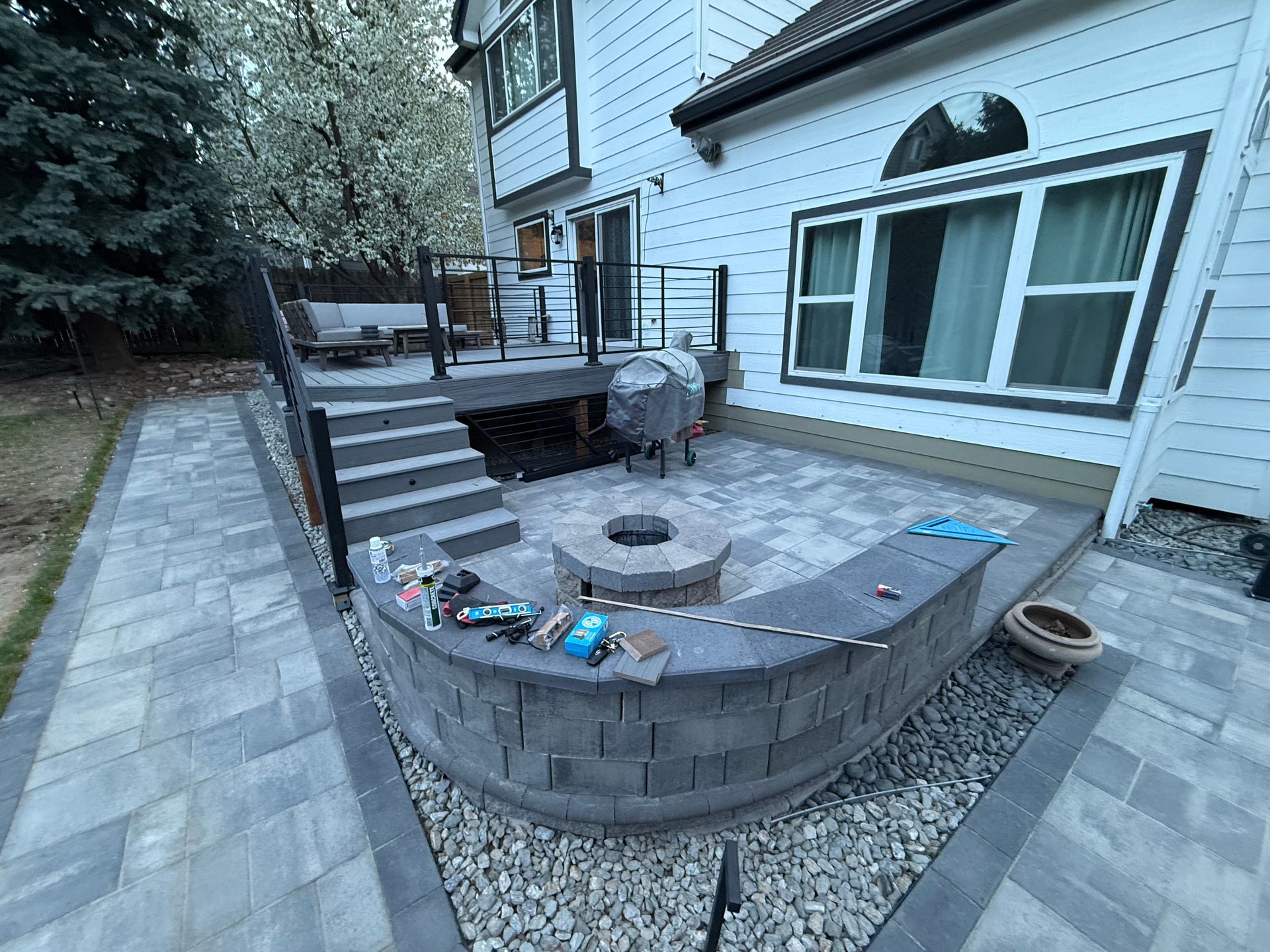 A patio with a fire pit and stairs in front of a house.