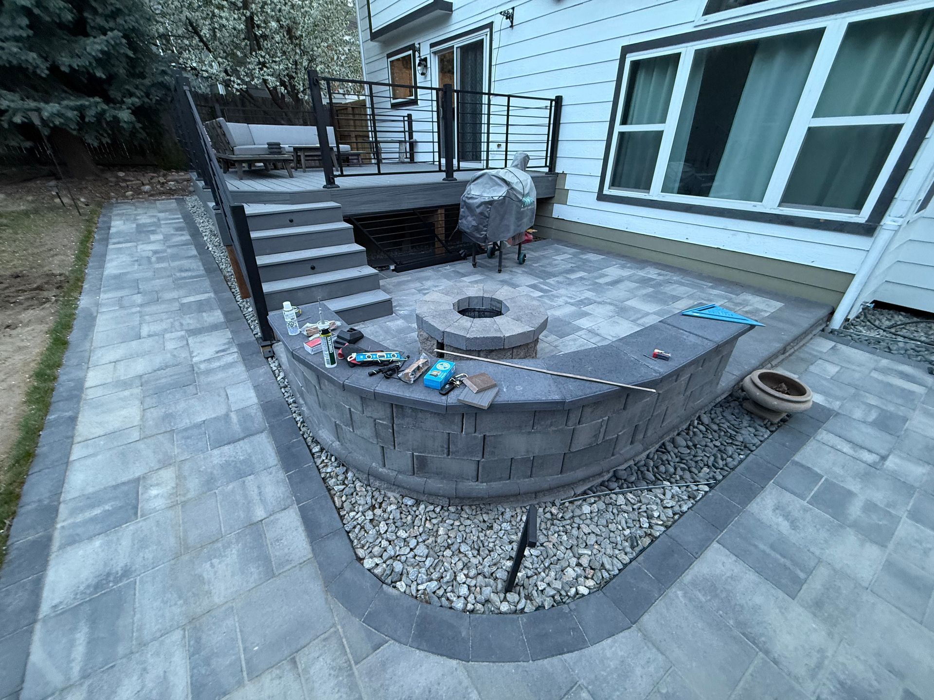 A patio with a fire pit and stairs in front of a house.