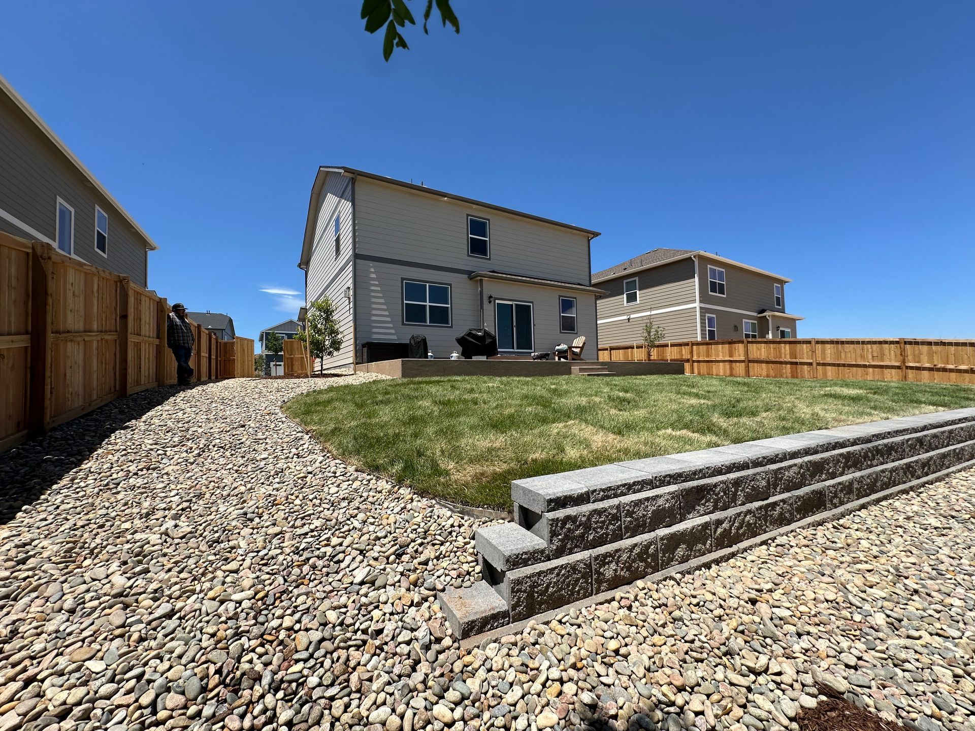 A house with a fence and a gravel driveway in front of it.