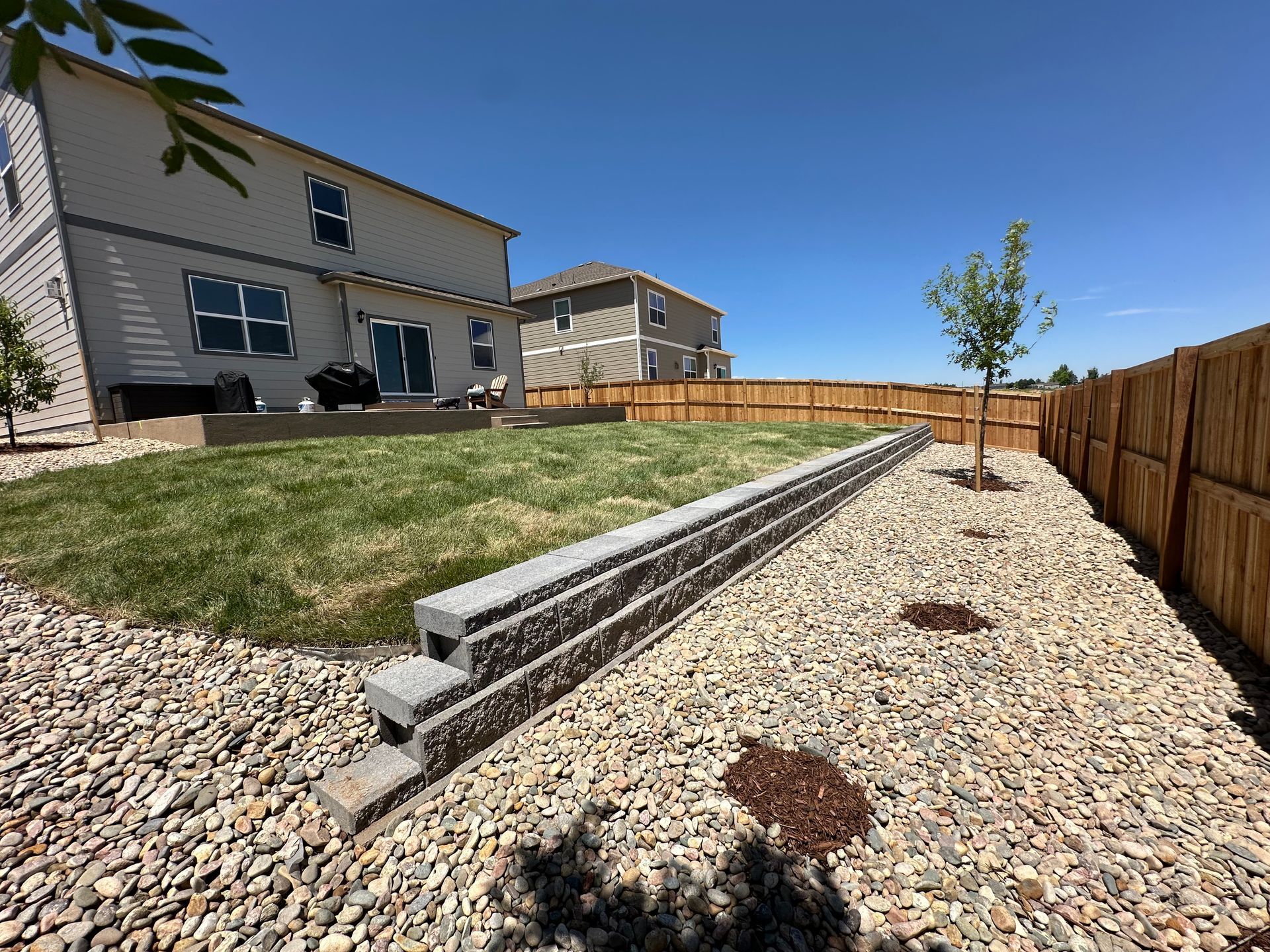 A large backyard with a fence and a house in the background.