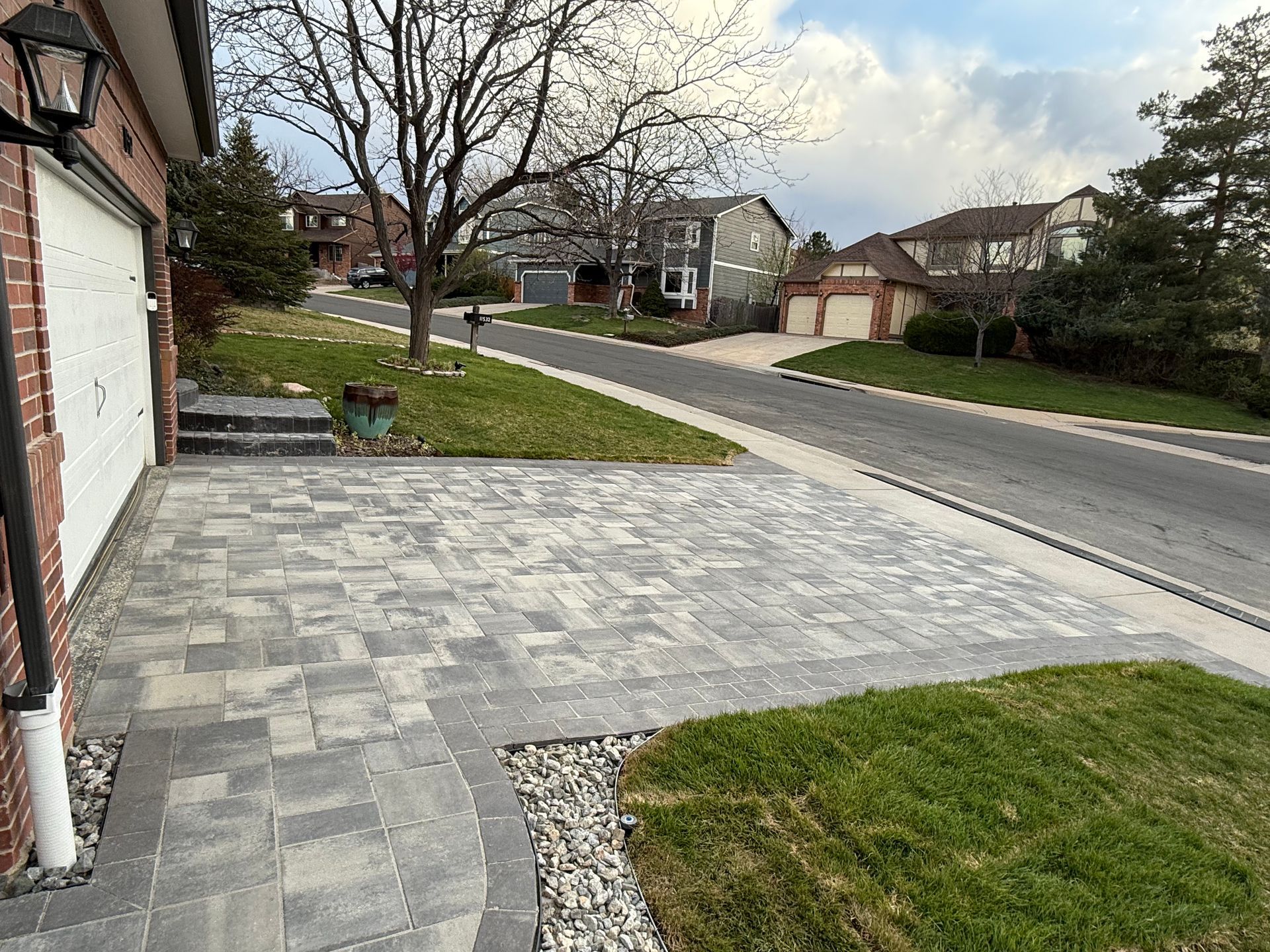 A driveway with a brick walkway leading to a garage in a residential neighborhood.