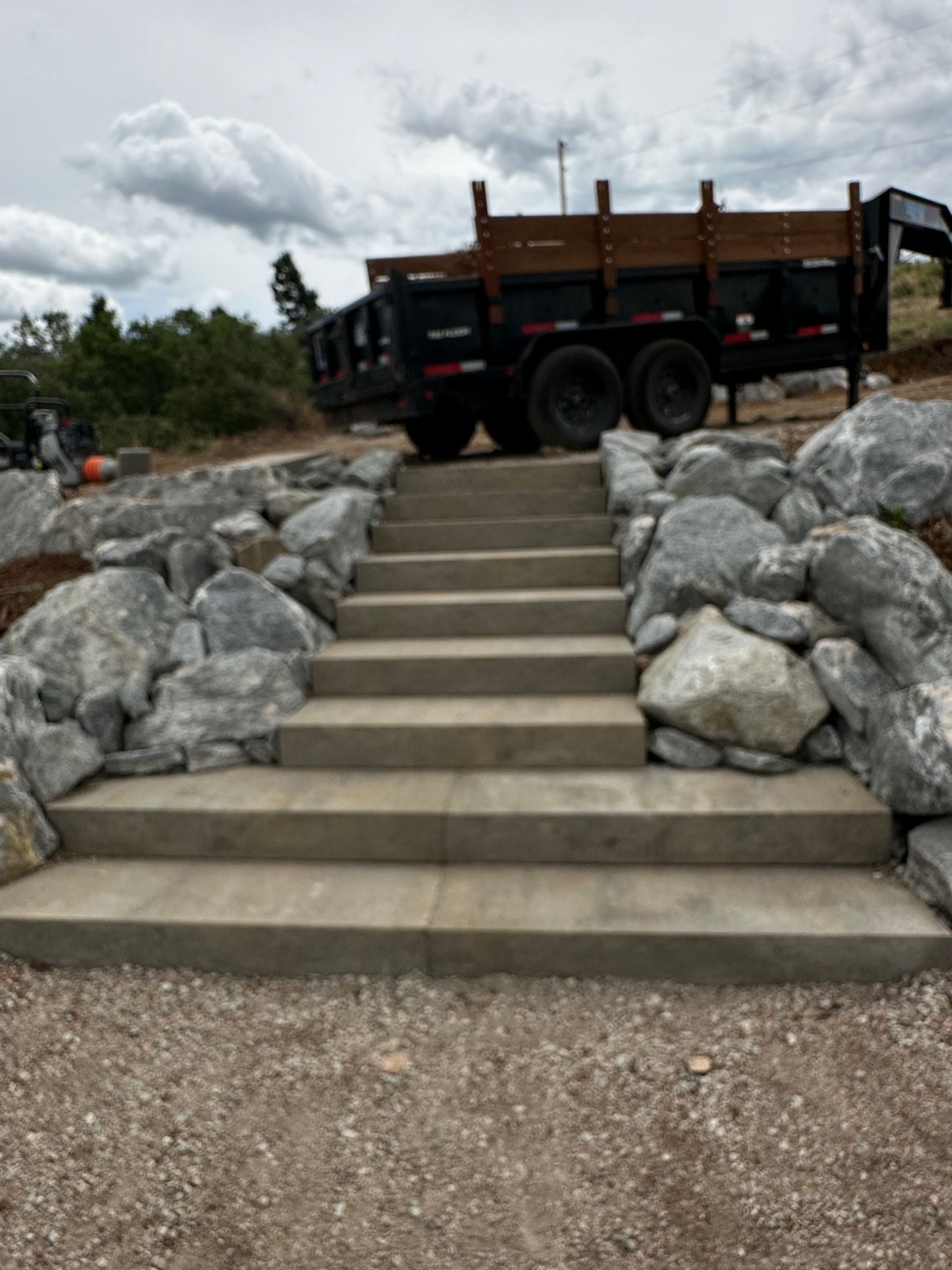 A dump truck is parked next to a set of stairs surrounded by rocks.