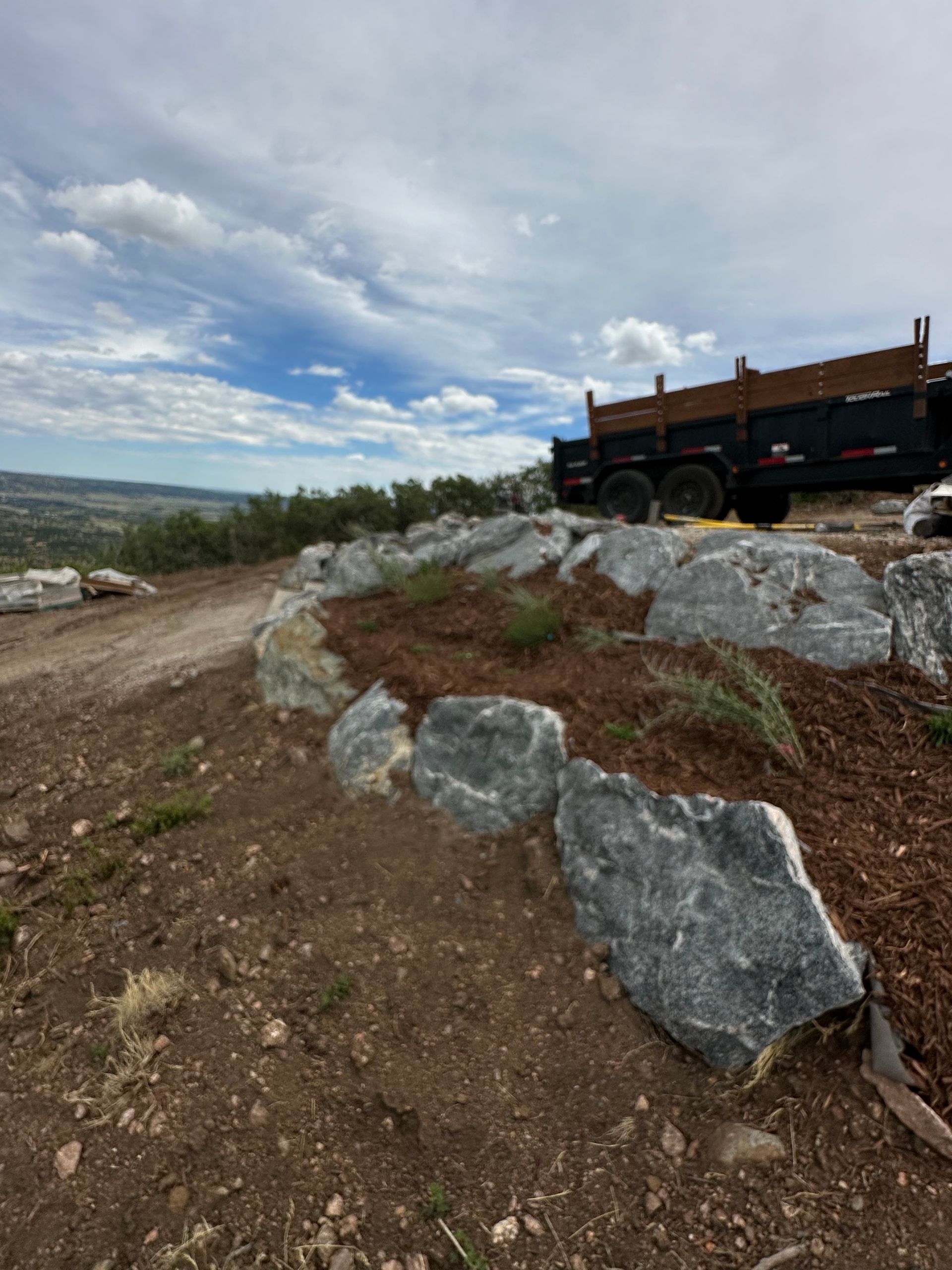 A dump truck is parked on top of a rocky hill.