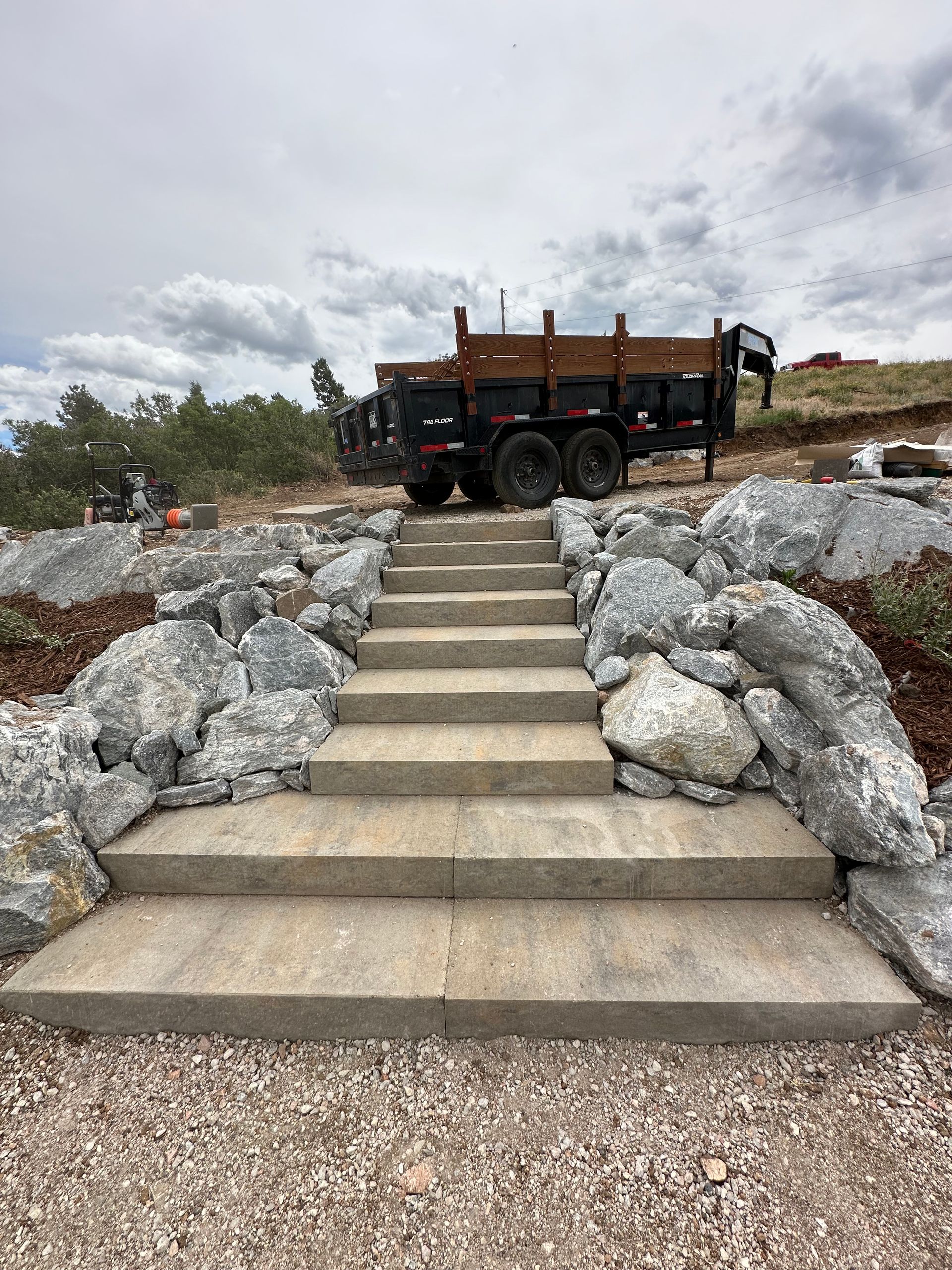 A truck is parked on top of a set of stairs surrounded by rocks.