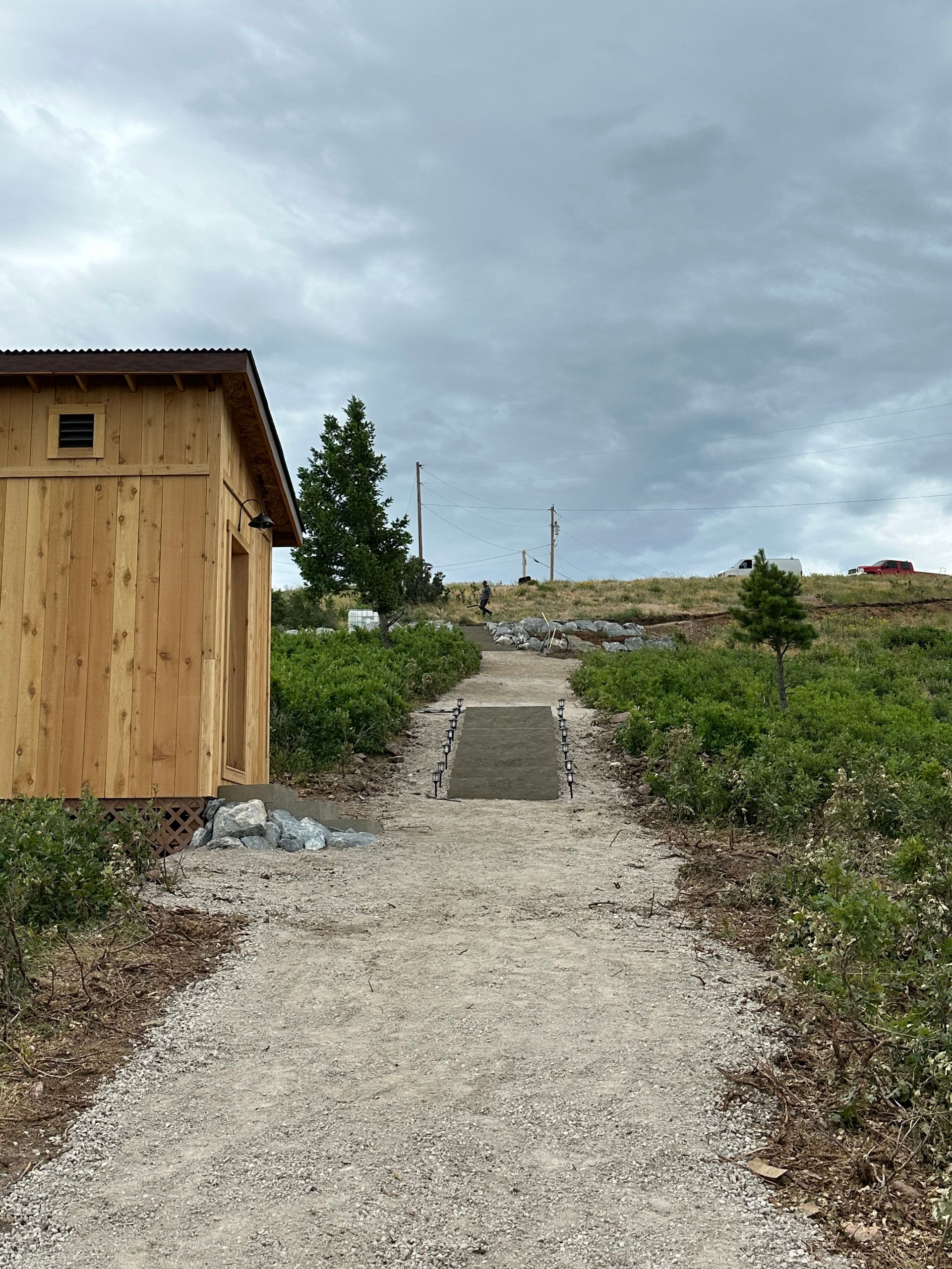 There is a path leading to a wooden building in the middle of a field.