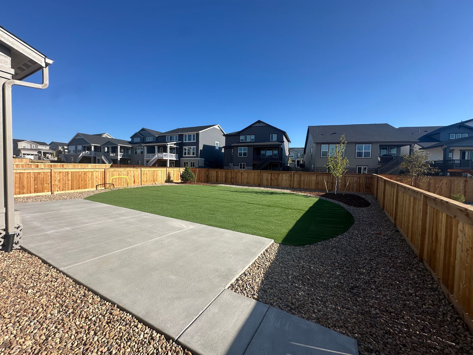 A backyard with a concrete walkway and a wooden fence