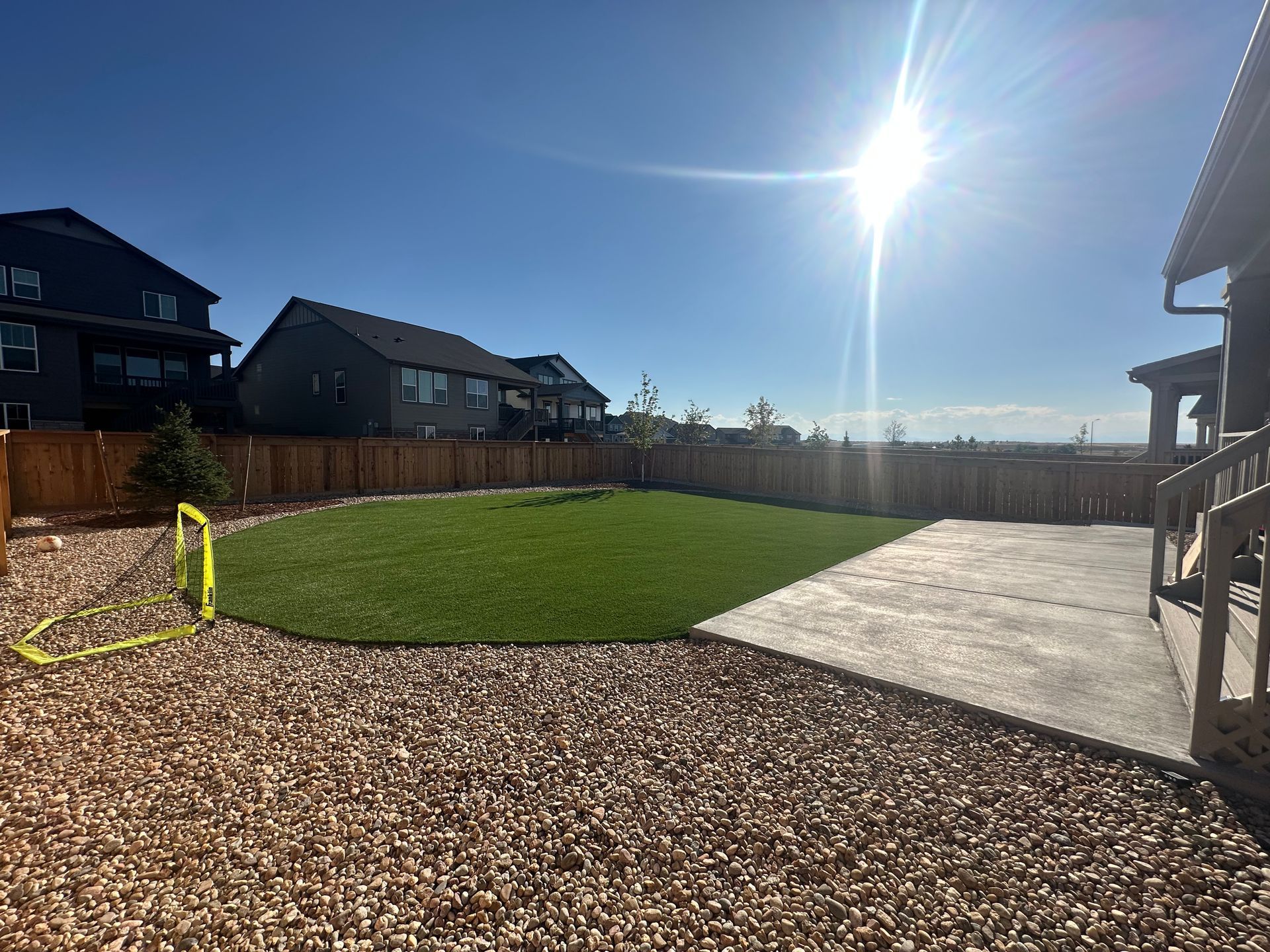 A backyard with a large lawn and a soccer goal.