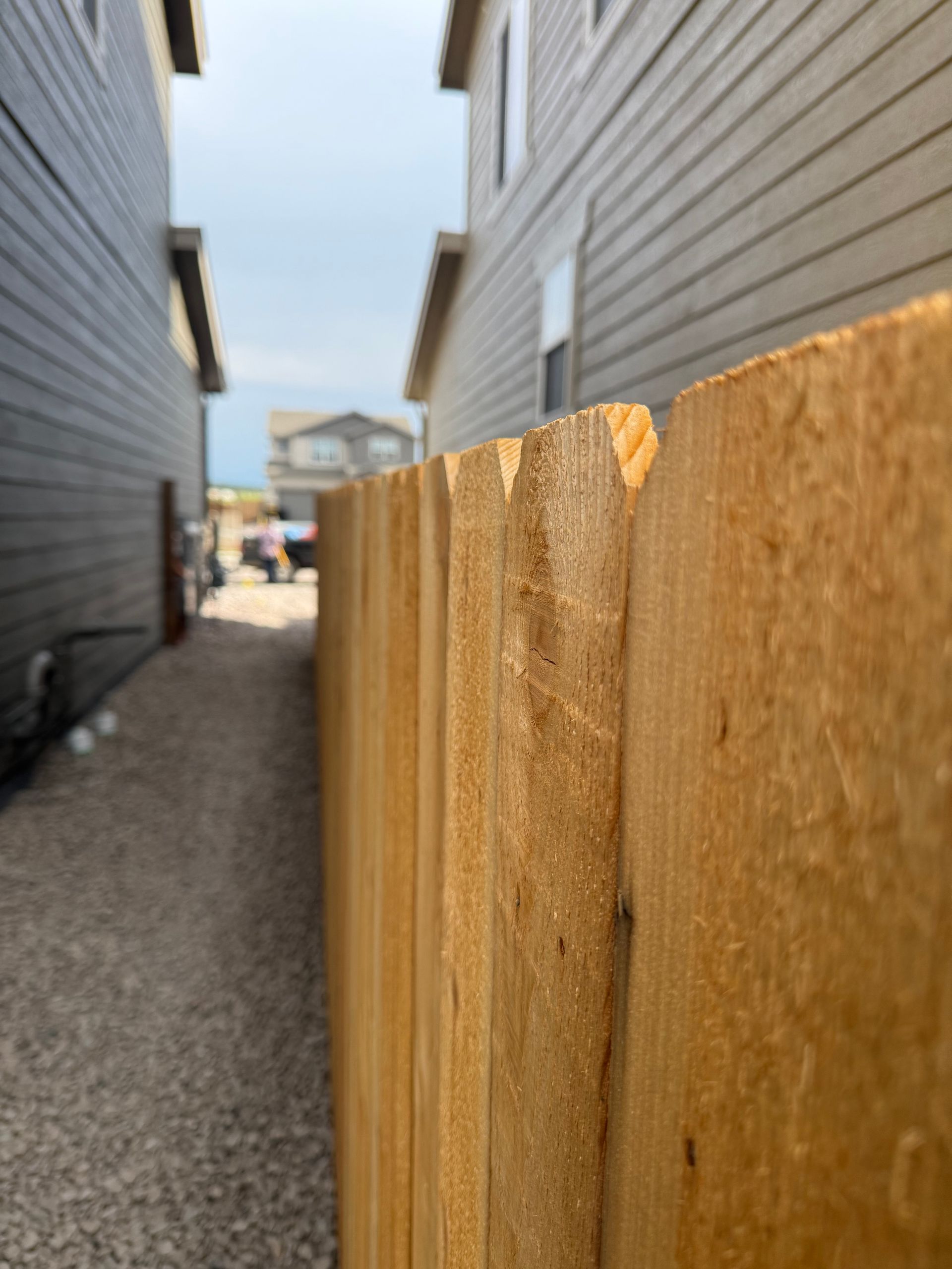 A close up of a wooden fence between two houses.