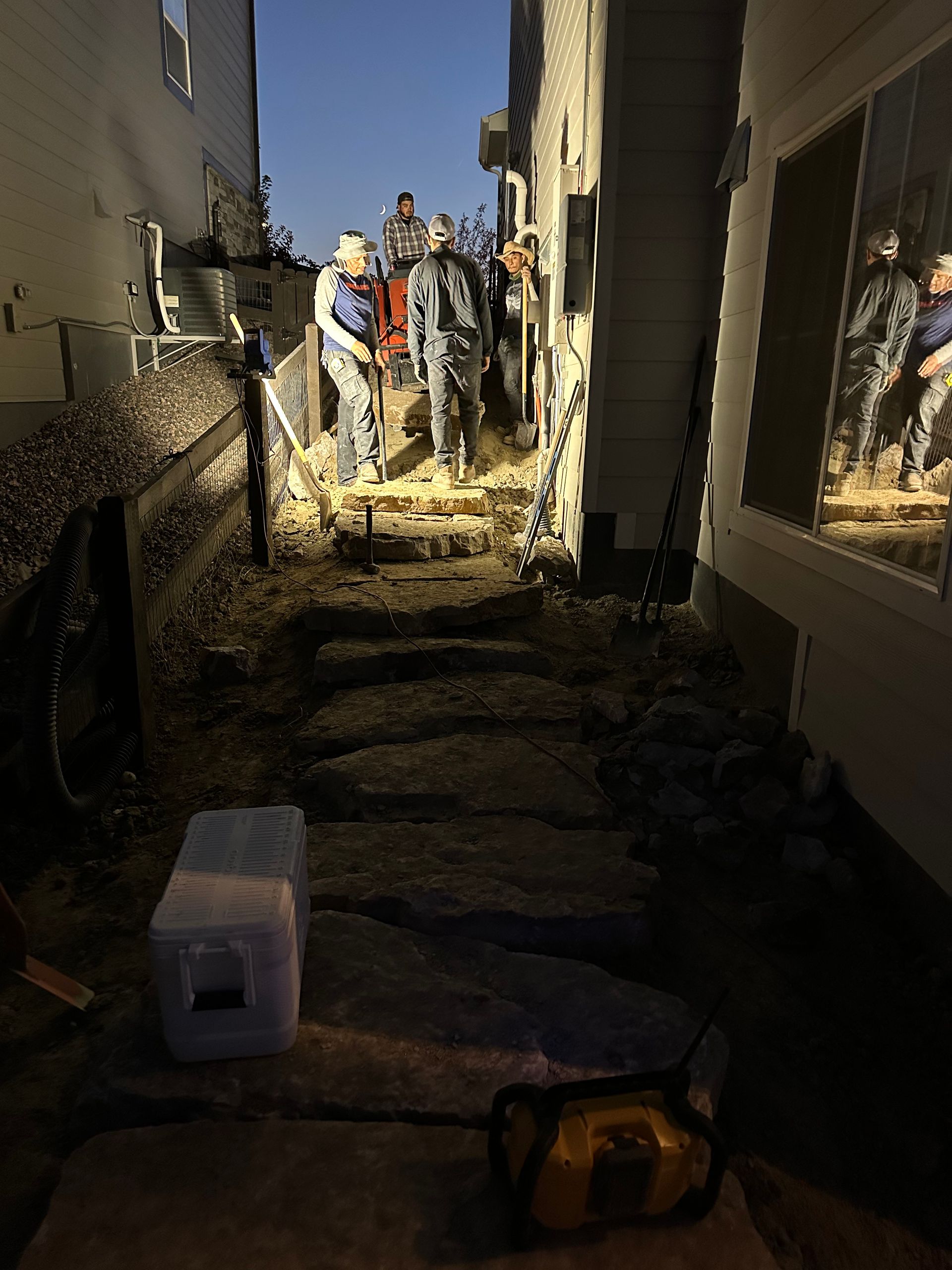 A group of construction workers are working on a sidewalk next to a building.