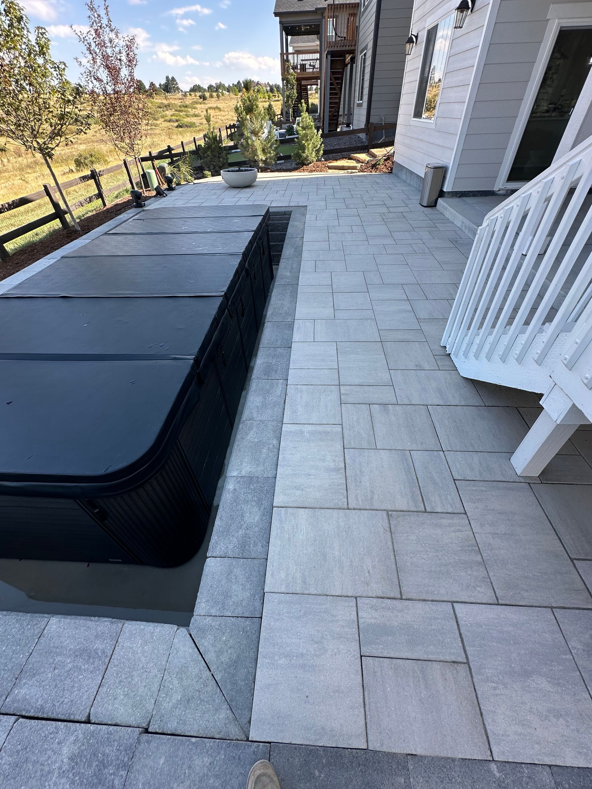 A hot tub is sitting on a patio next to a white chair.