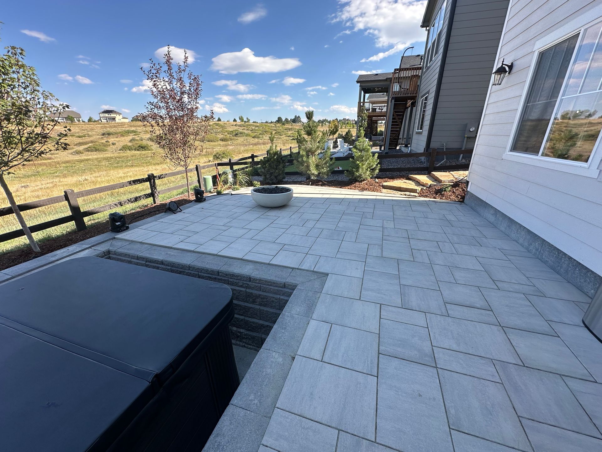 A patio with a hot tub and a house in the background.