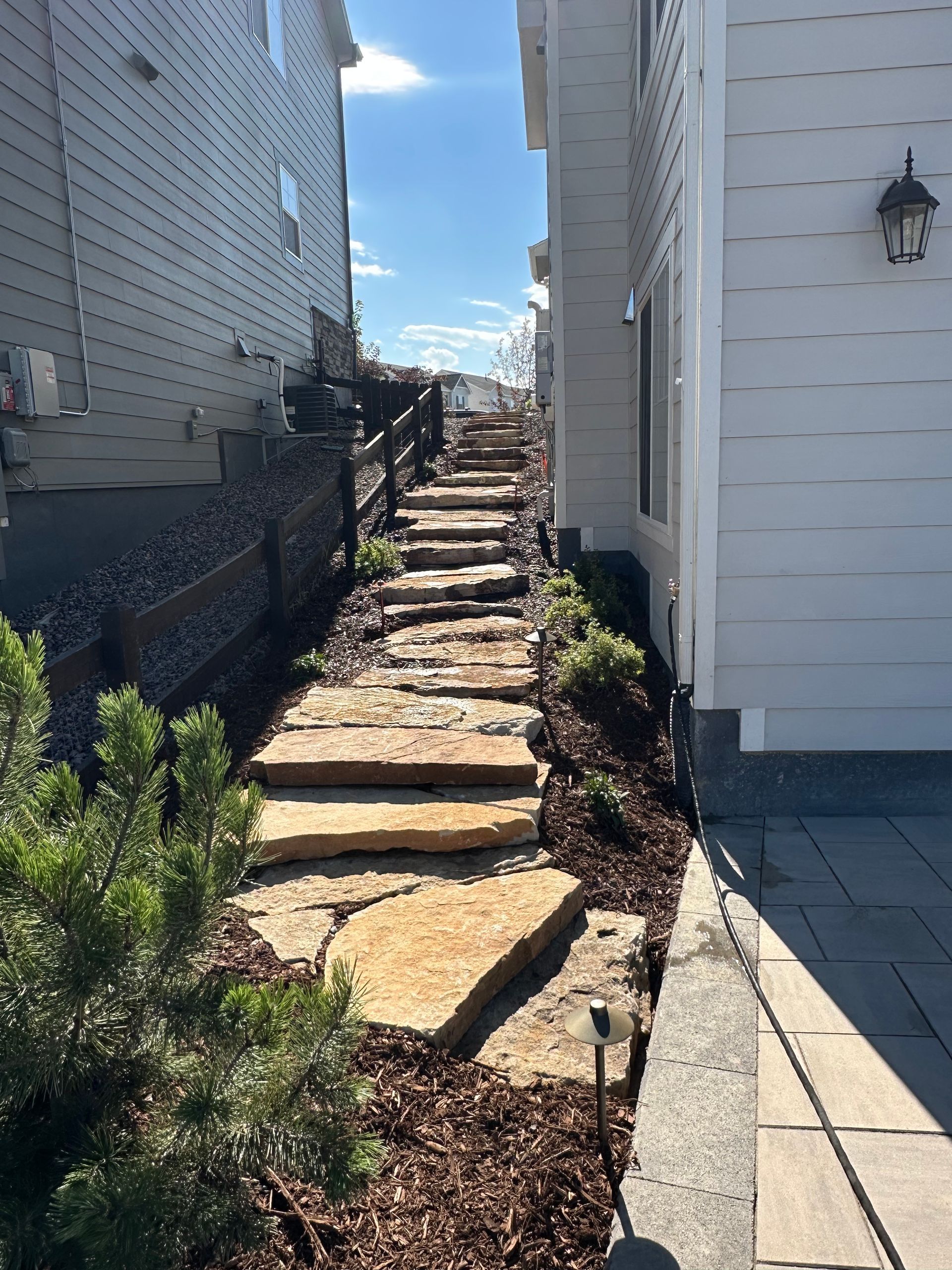A stone walkway between two houses on a sunny day.