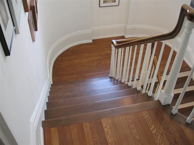 A wooden staircase with a white railing and a picture on the wall.