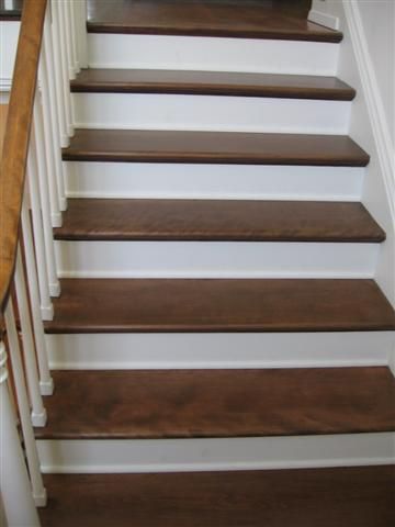 A set of stairs with wooden steps and white railing.