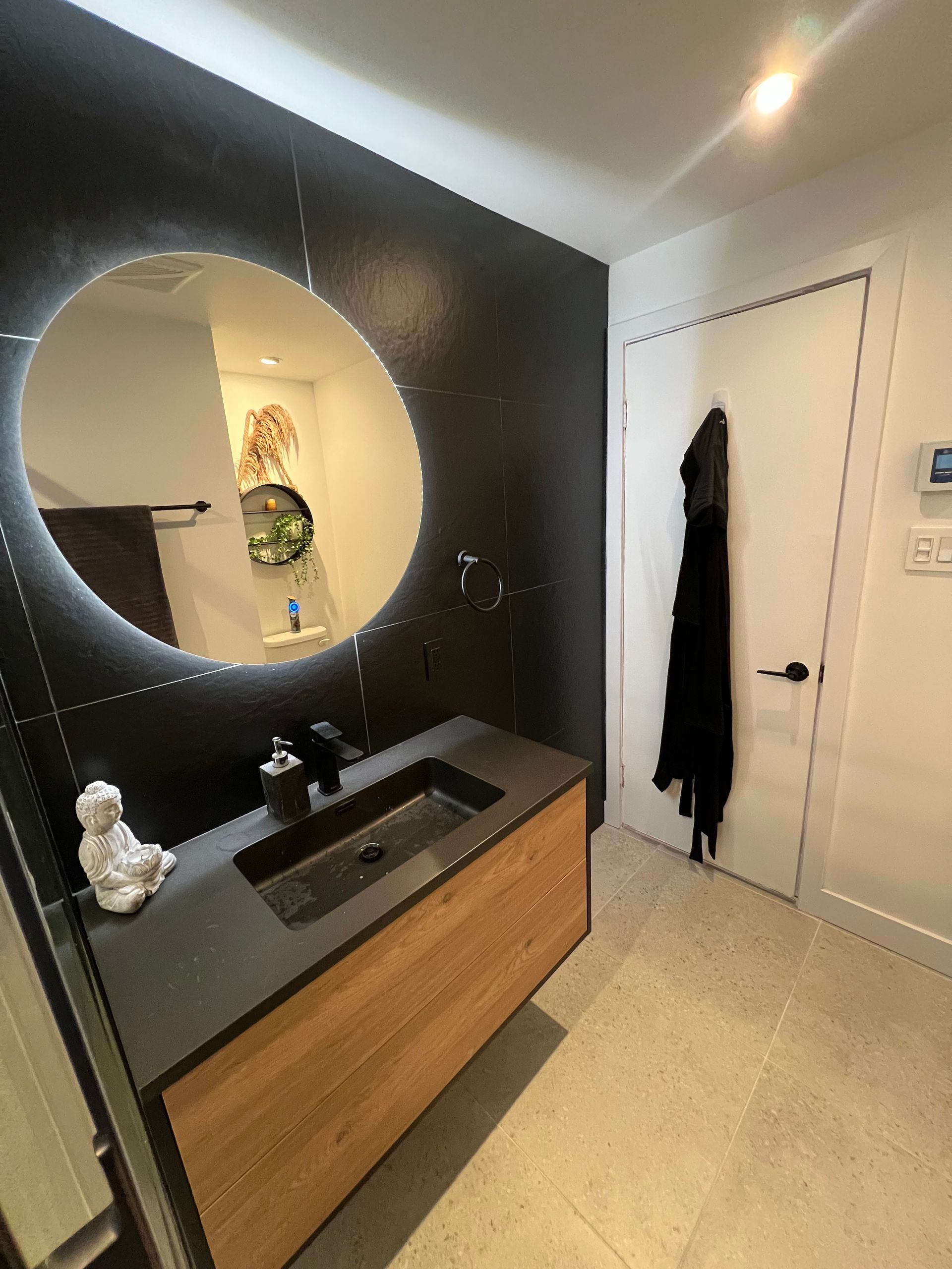 Une salle de bain avec un lavabo, un miroir et une porte.