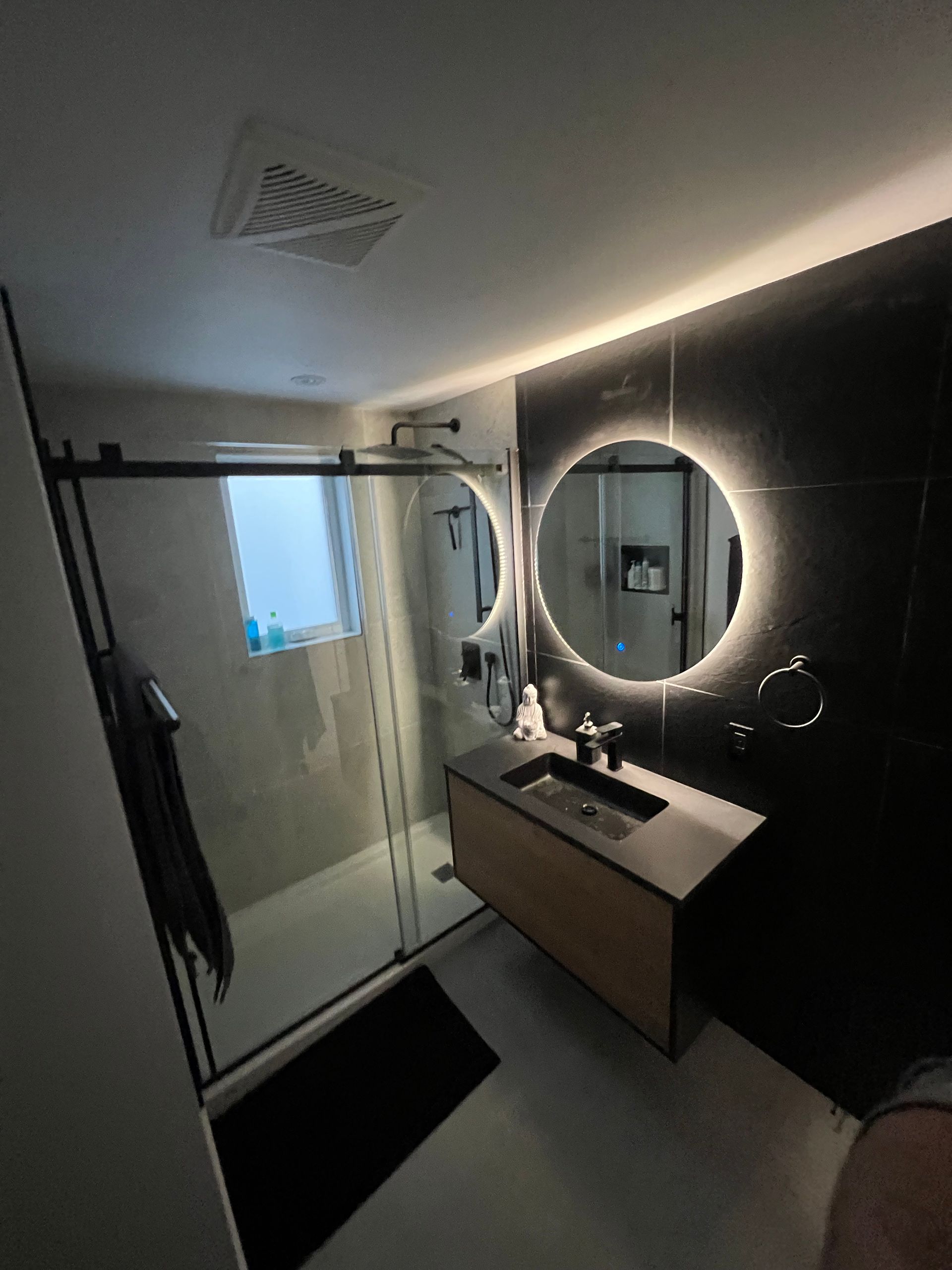 Une salle de bain avec lavabo, miroir et douche.