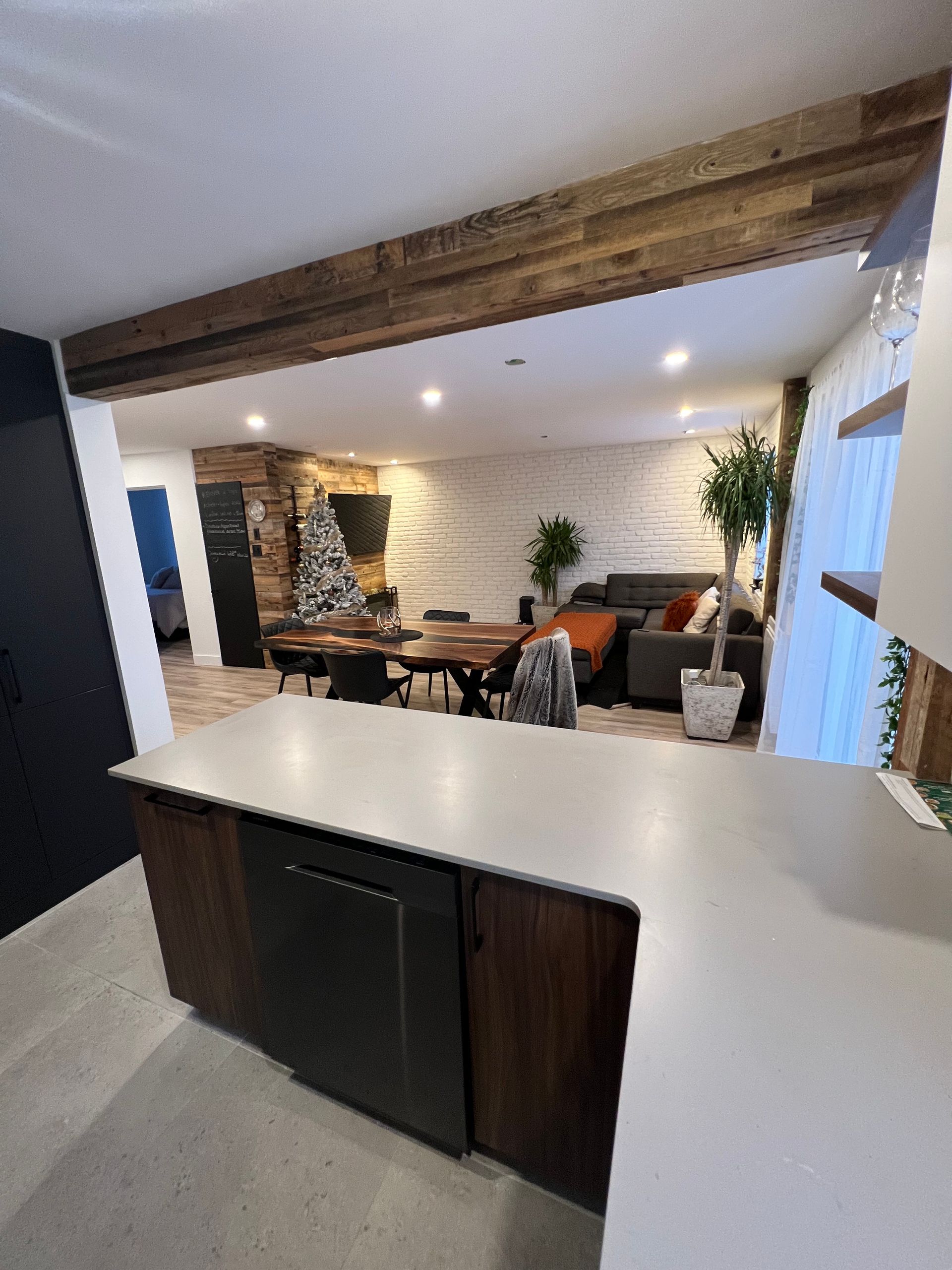 Une cuisine avec un grand îlot au milieu et un salon en arrière plan.