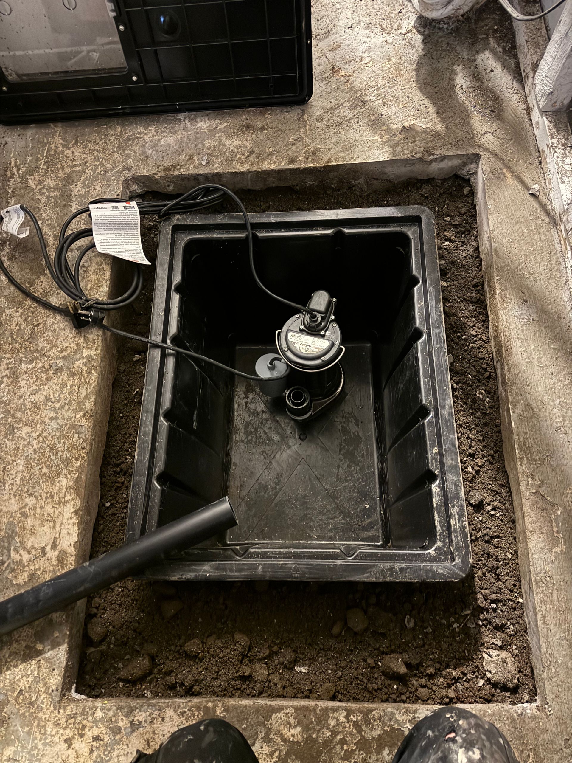 Une boîte noire avec une pompe à l'intérieur se trouve dans un trou dans le sol.