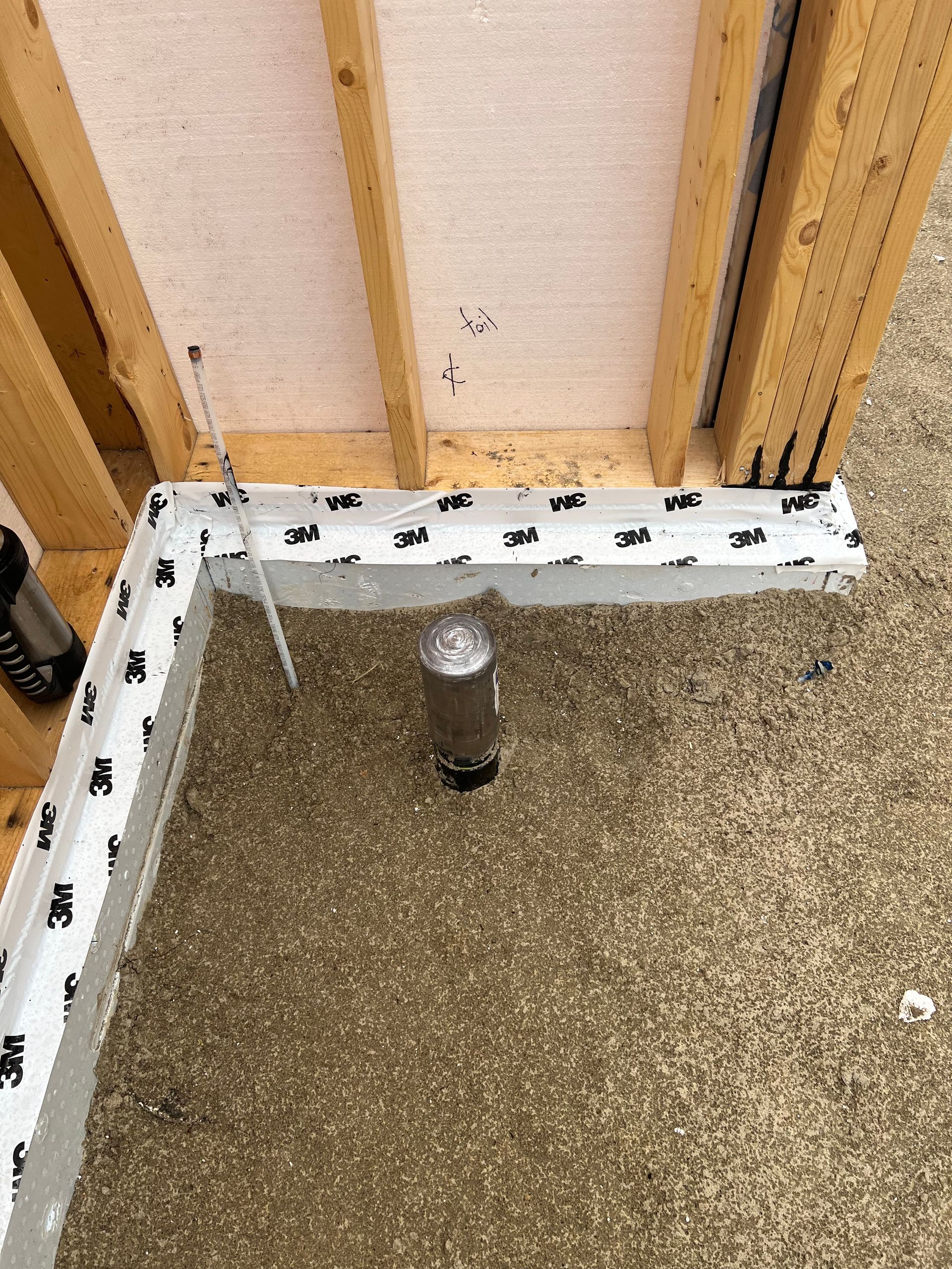 Une bouteille de peinture en aérosol est posée sur le sol à côté d'un mur en bois.