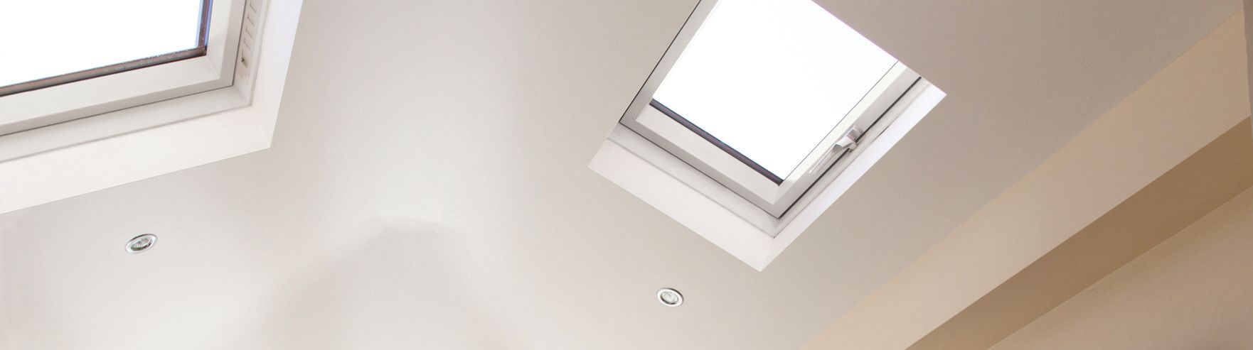 Looking up at a skylight in a white room.