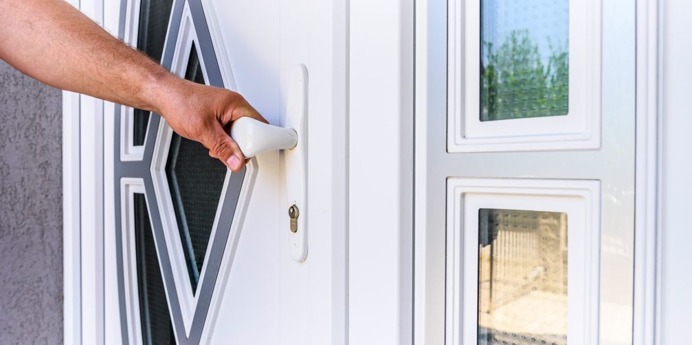 A person is opening a white door with a key.