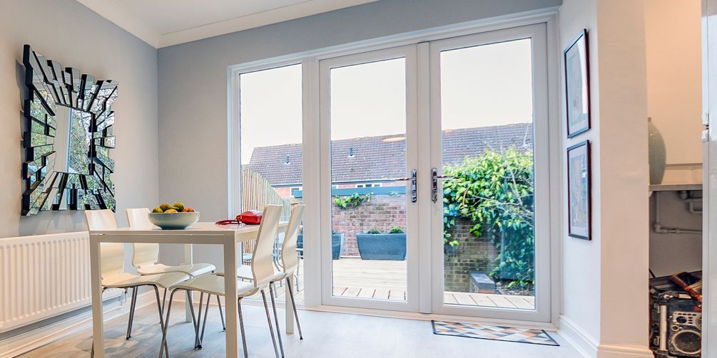 A dining room with a table and chairs and a clock on the wall.