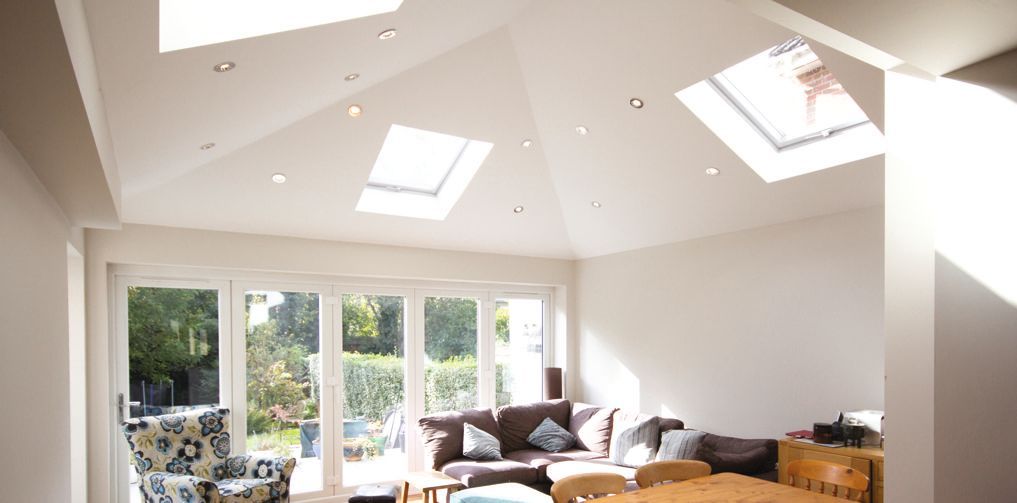 A living room with a couch , chair , table and skylights.