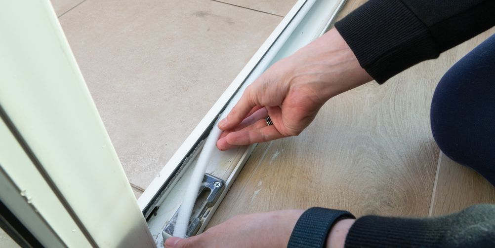 A person is installing a sliding glass door on a wooden floor.