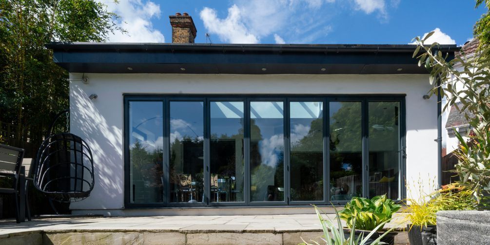 The back of a house with a lot of windows and a patio.