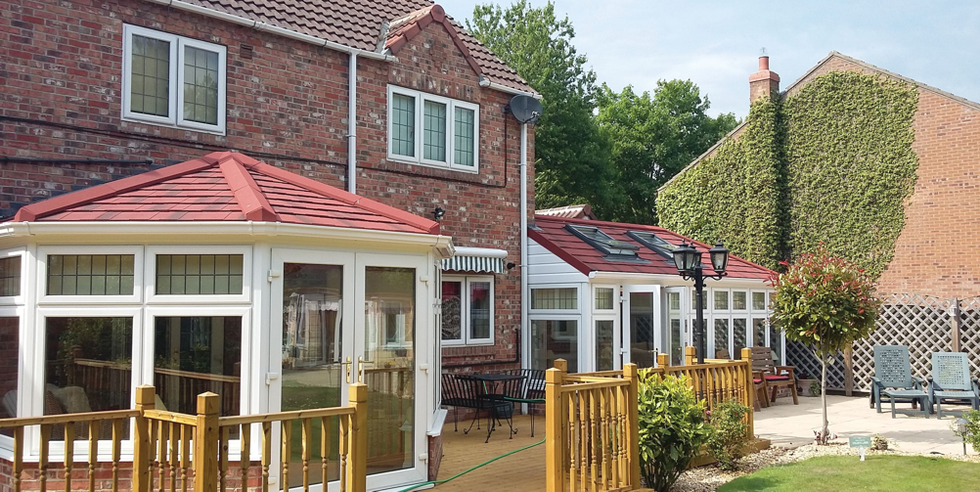 A large brick house with a white conservatory and a red roof