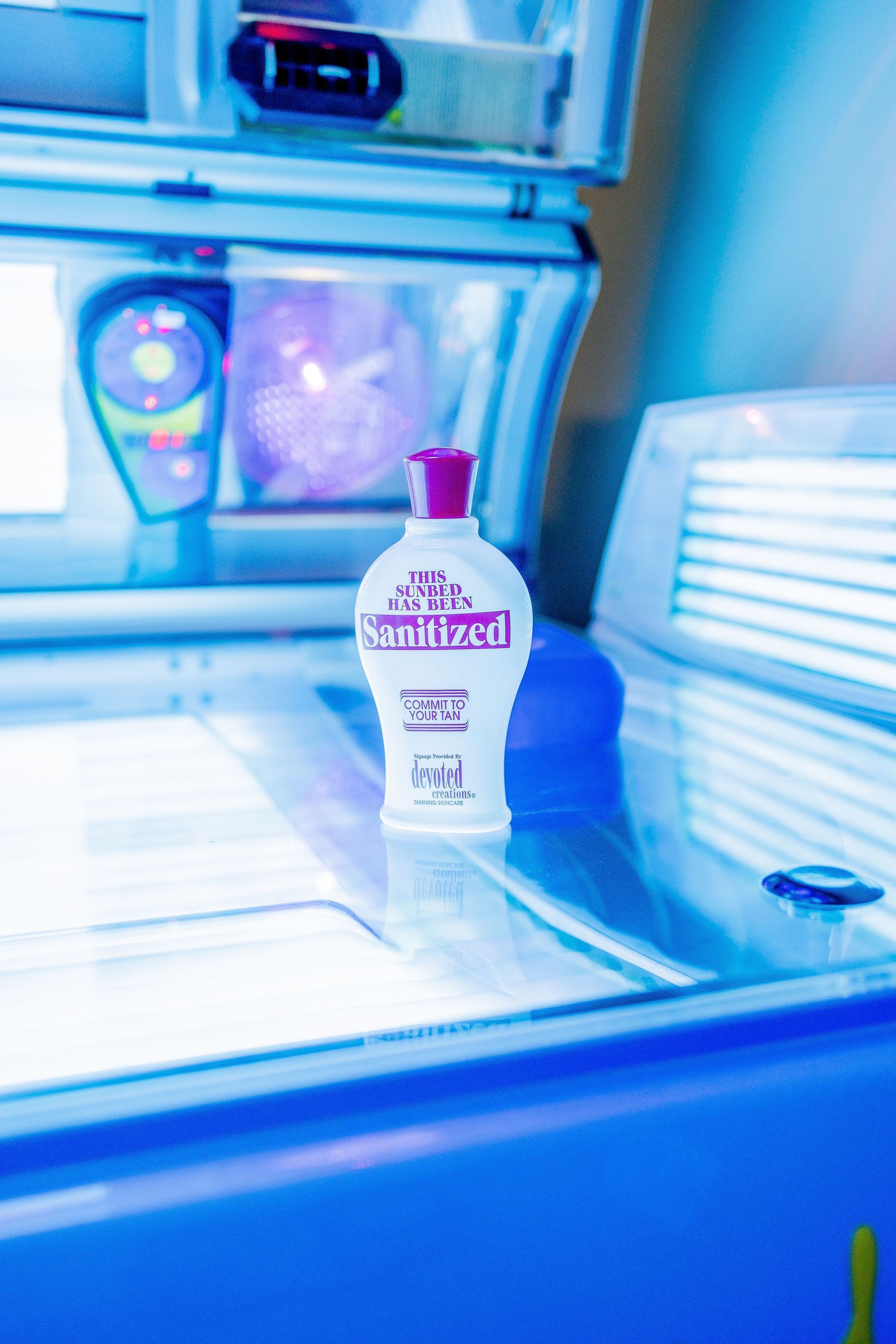 Bottle of lotion on a tanning bed, bathed in blue light.