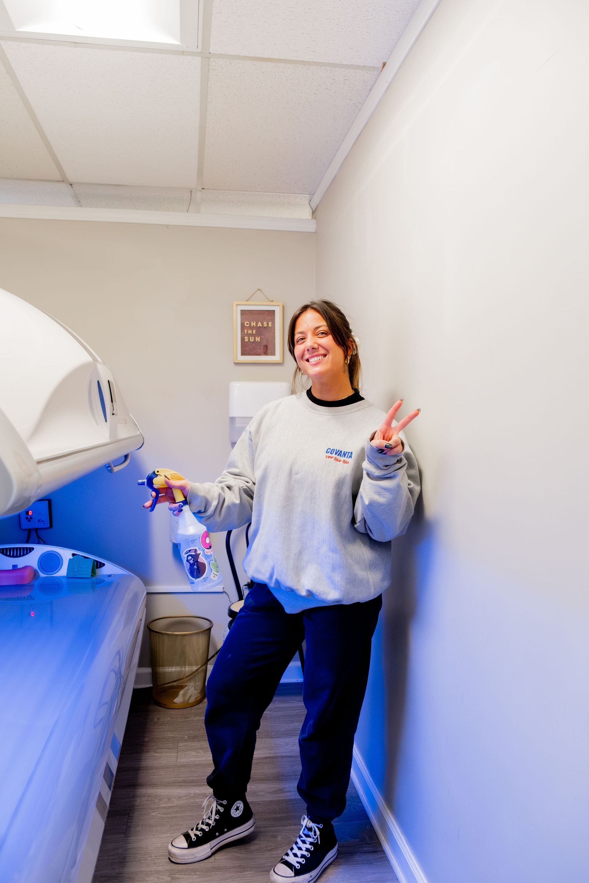 Woman smiling, leaning on wall, next to floatation tank; interior spa setting.